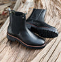 Barbour EVIE Womens Boots Black side view showcasing ankle boots with leather and nylon upper on rustic surface.