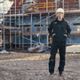 Apache QUEBEC Mens Over Trousers Black worn by a worker at a construction site, side view showing construction details.