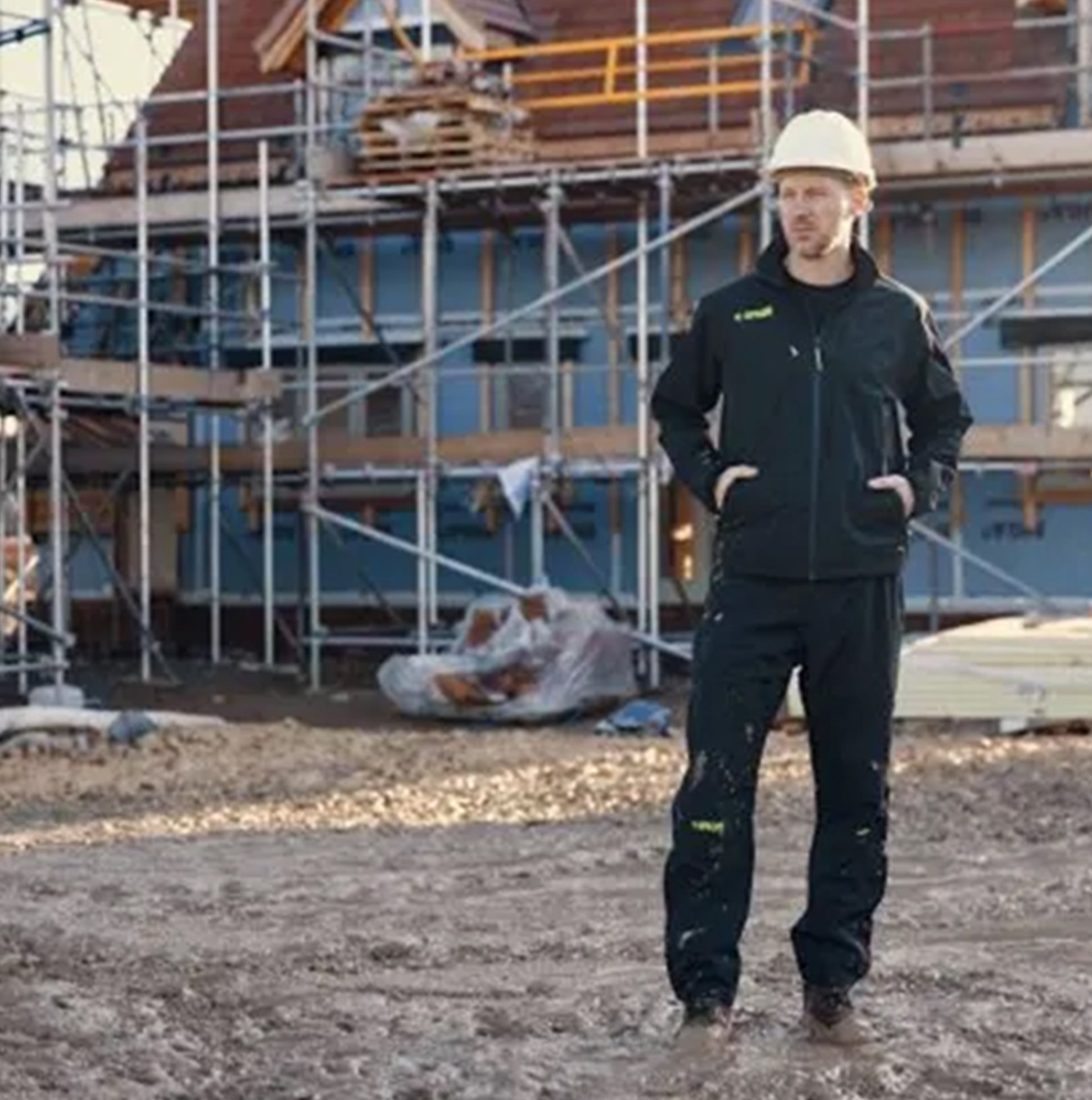 Apache QUEBEC Mens Over Trousers Black worn by a worker at a construction site, side view showing construction details.