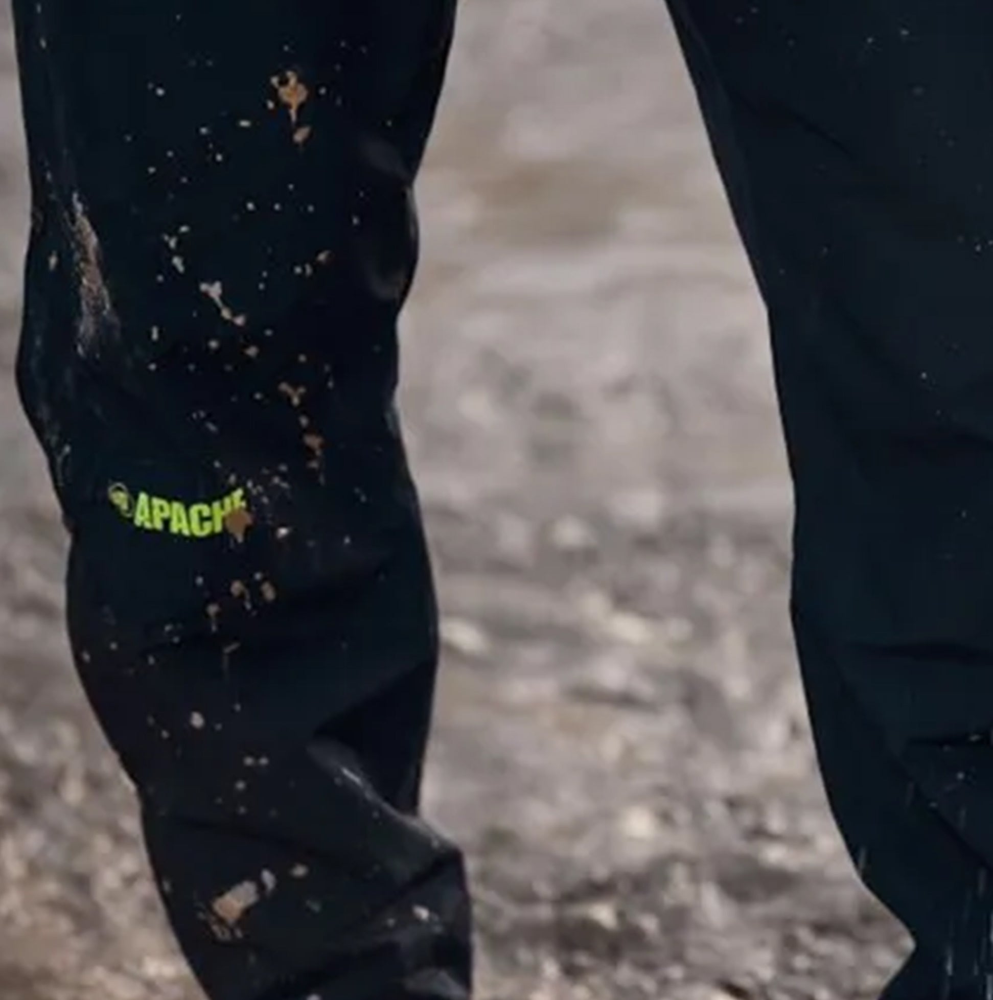 Apache QUEBEC Mens Over Trousers Black side view showing logo detail on fabric with dirt stains.