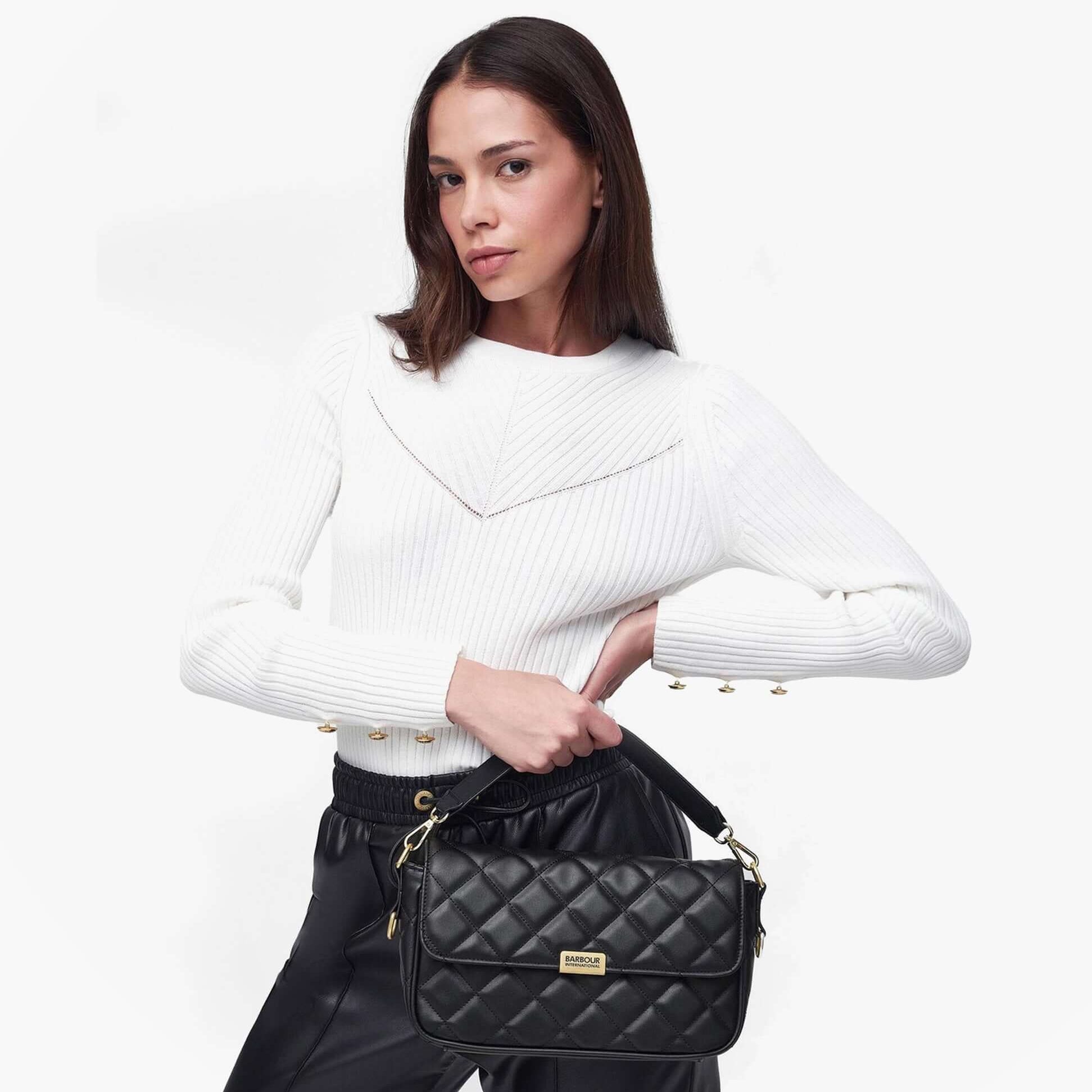 Barbour QUILTED SOHO Womens Crossbody Bag Black held by model wearing a white sweater, front view showcasing the bag's quilted design.