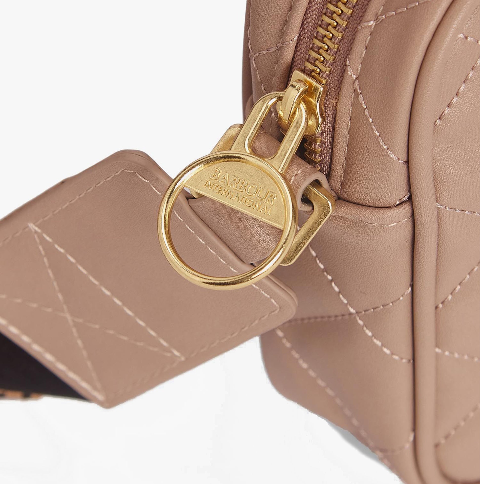Detail view of Barbour QUILTED SLOANE Womens Crossbody Bag Camel with gold zipper and logo charm.