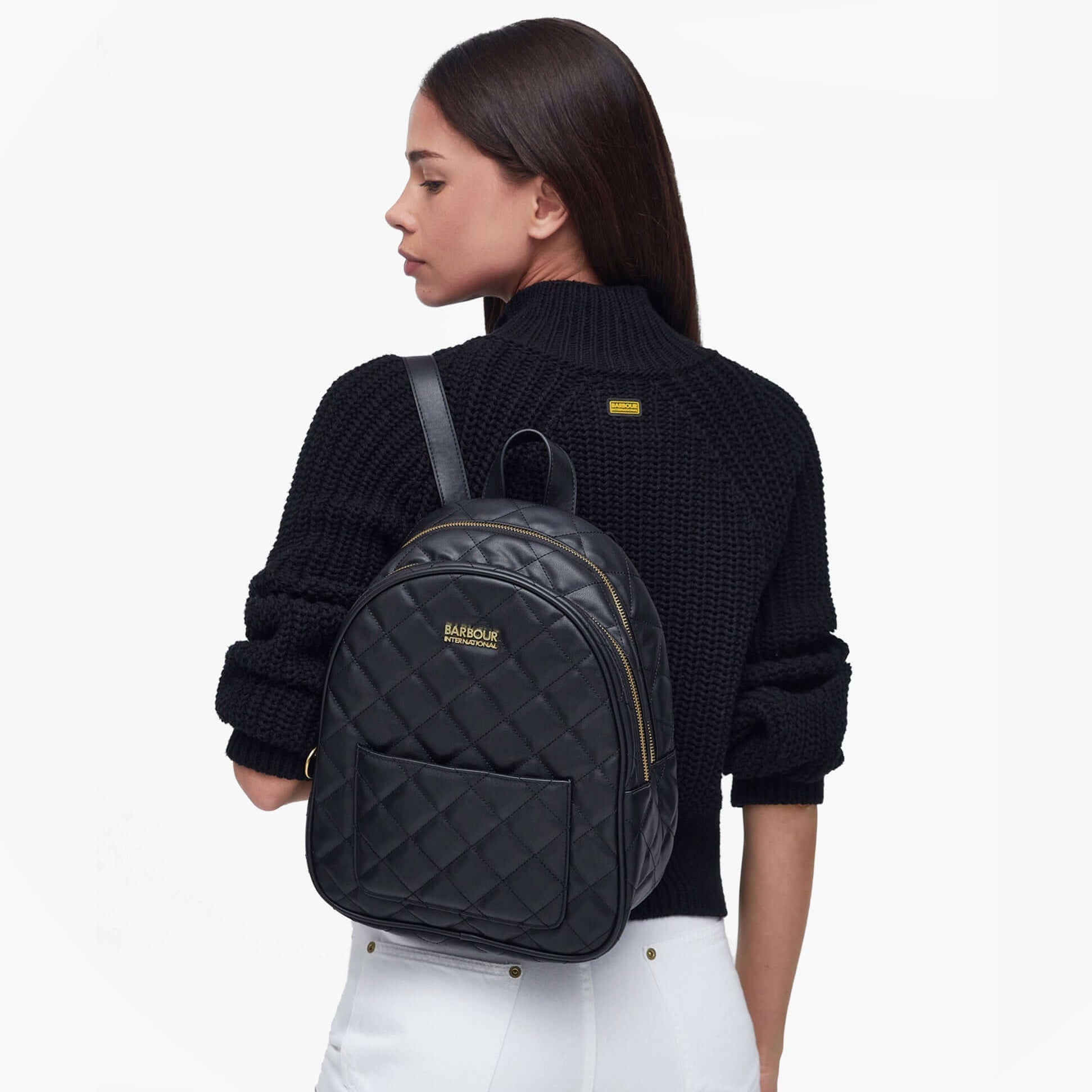 Barbour QUILTED UXBRIDGE Womens Backpack Black side view on model wearing a black sweater.