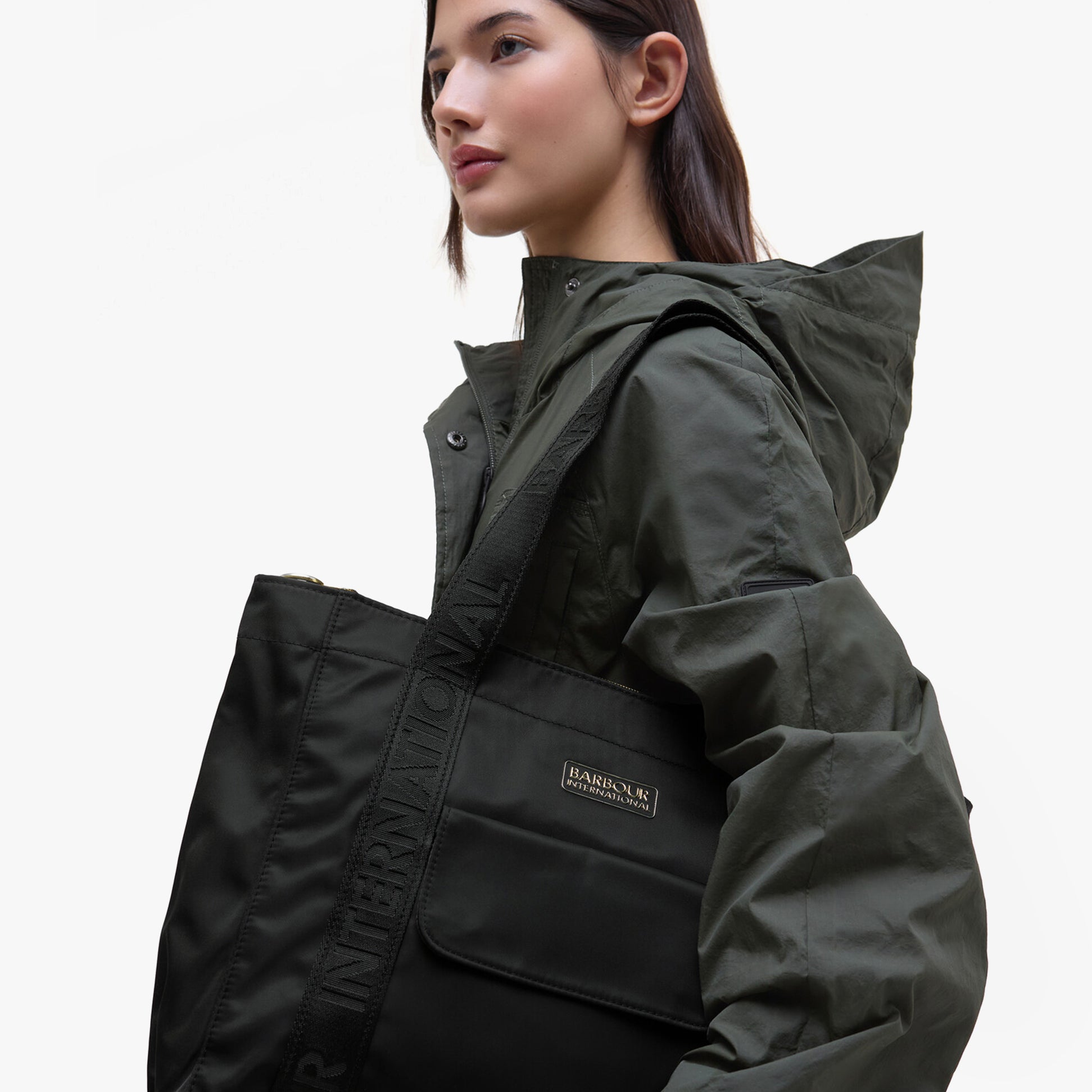 Barbour B.INTL QUALIFY Womens Tote Bag Black on model's shoulder, showcasing sleek design and logo detail.