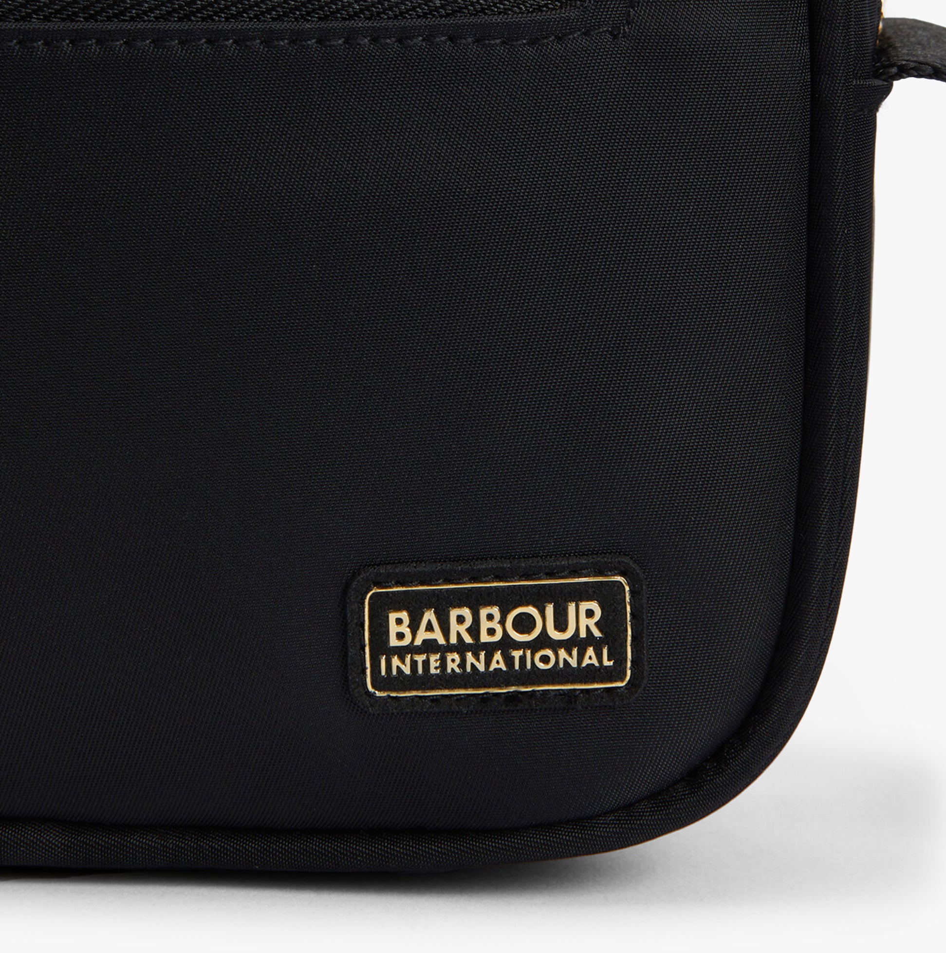 Detail view of Barbour B.INTL MICRO QUALIFY Womens Crossbody Bag Black logo on black nylon material.