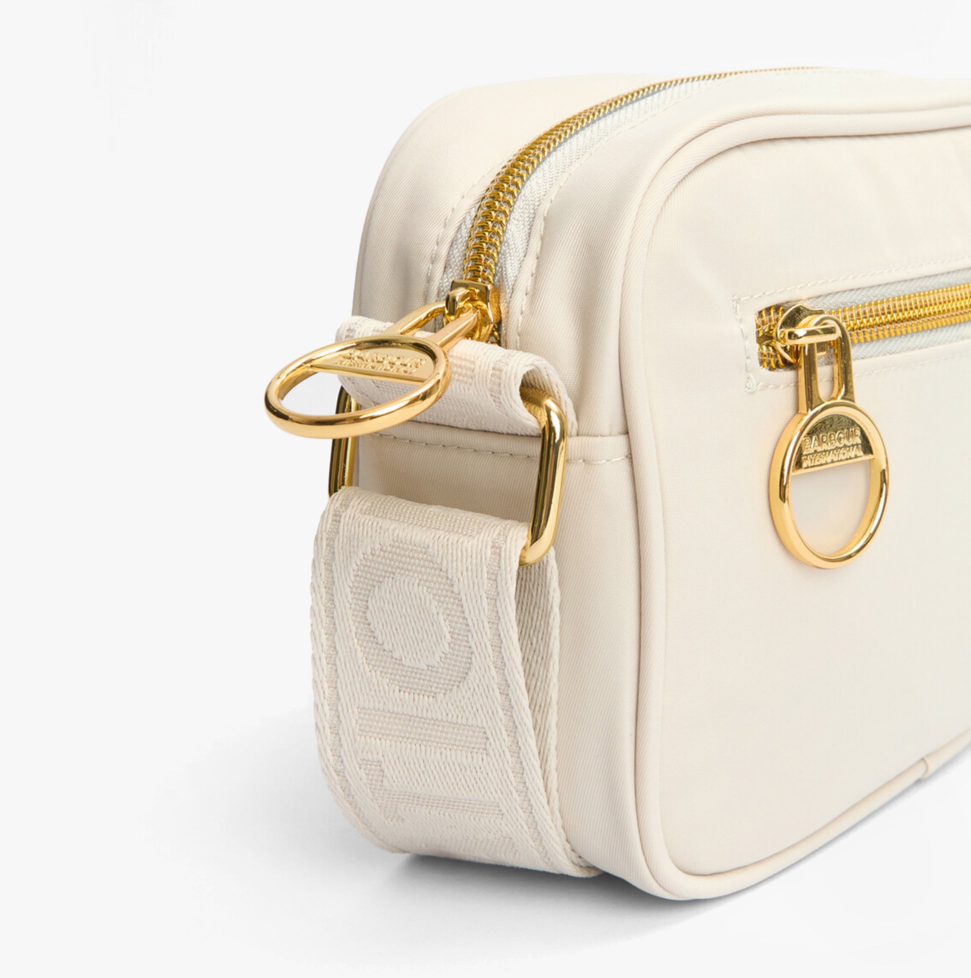 Barbour B.INTL MICRO QUALIFY Womens Crossbody Bag Light Pearl side view with adjustable strap and gold hardware.