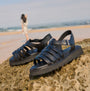 Barbour OTTERBURN Womens Fisherman Sandals Black side view on rocky beach with model in background