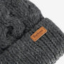 Barbour PENSHAW Womens Pom-Pom Beanie Charcoal detail view showcasing cable-knit texture and logo-embossed leather badge.