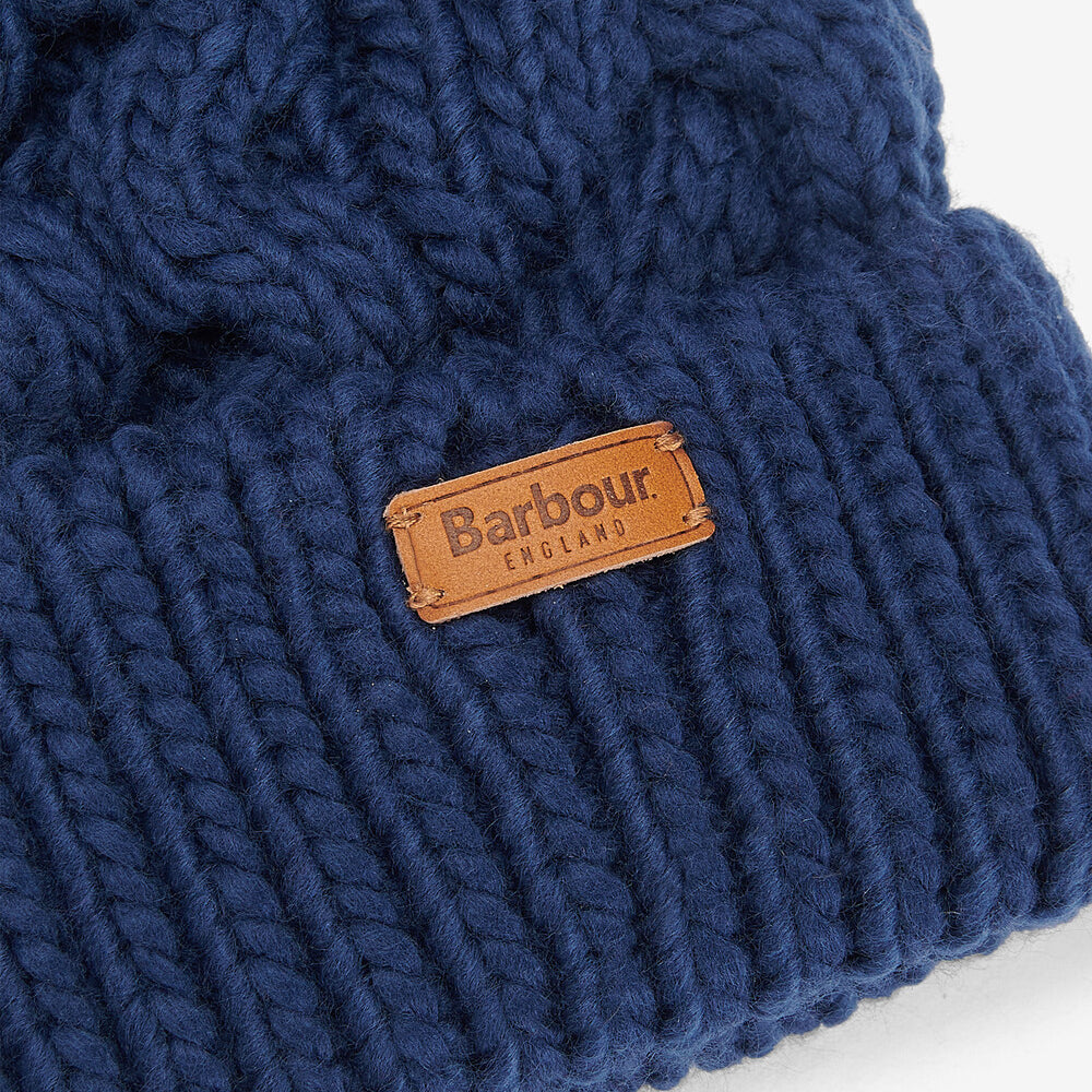 Barbour PENSHAW Womens Pom-Pom Beanie Navy close-up detail view of the logo-embossed leather badge.