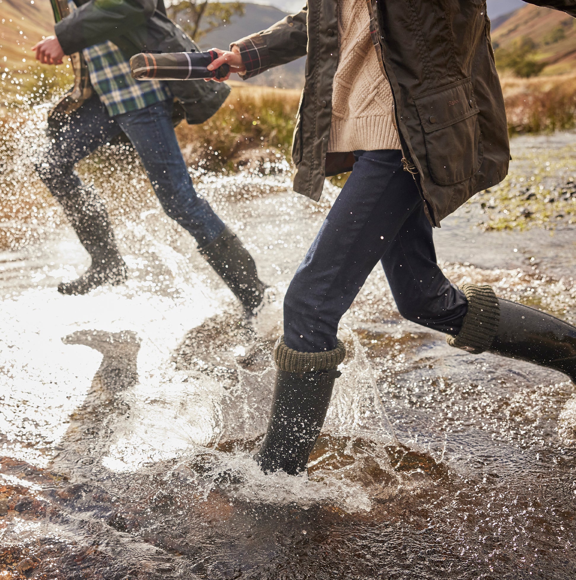 Barbour BEDE Womens Tall Wellies Olive in action, splashing through water, showcasing waterproof design and comfort.