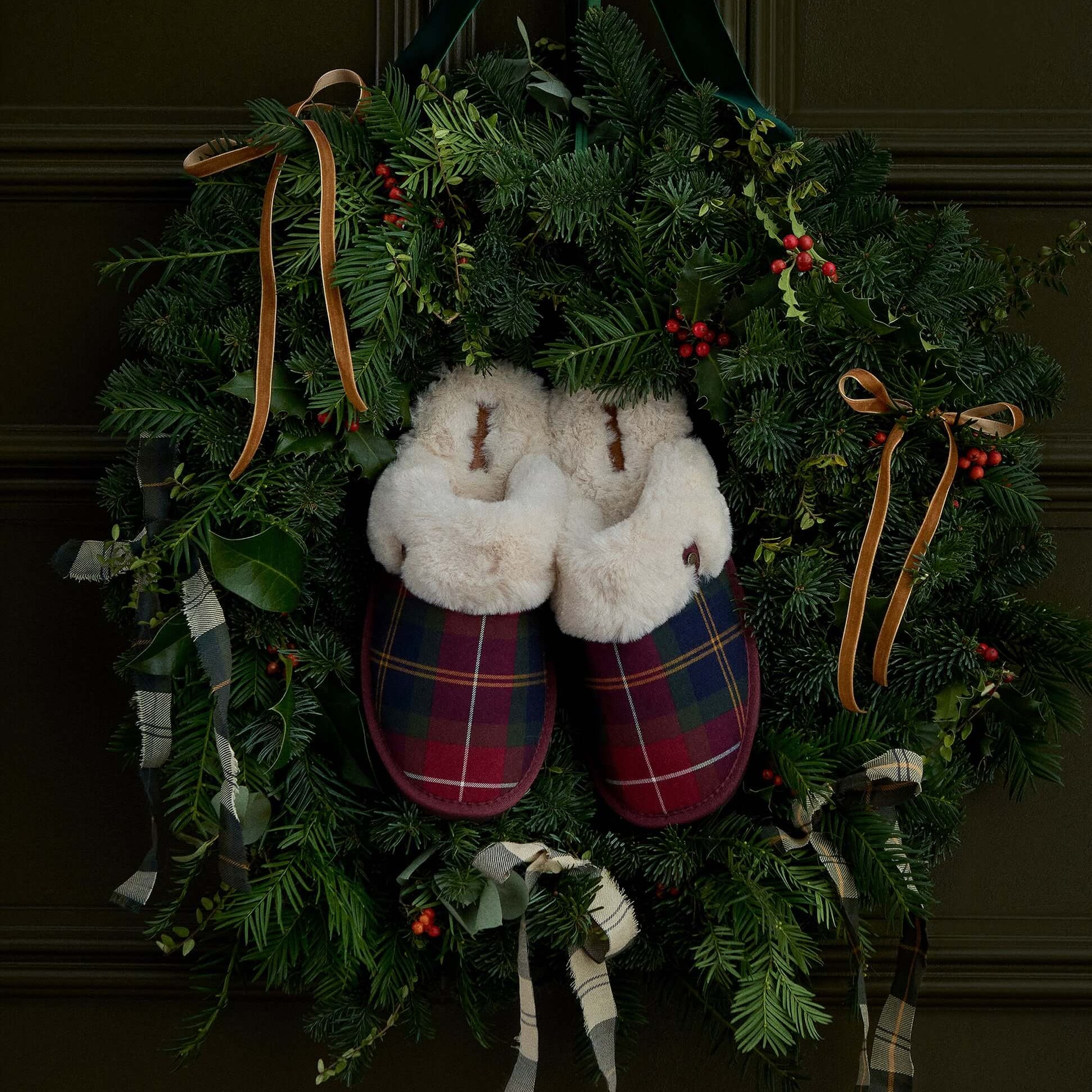 Barbour CLAUDIA Womens Mule Slippers Winterberry Tartan hanging on a festive wreath, showcasing their cozy design and tartan pattern.