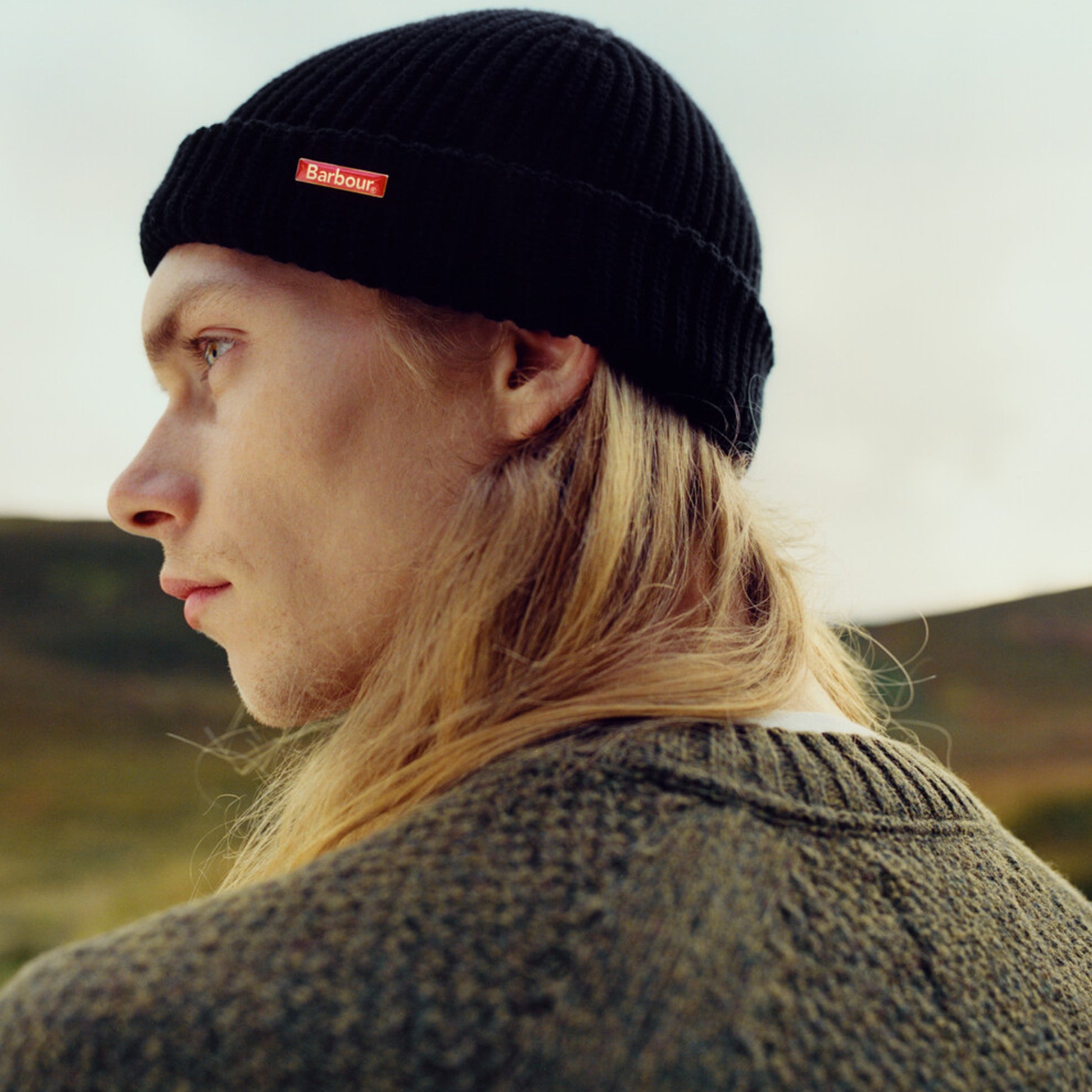 Barbour MOSELY Mens Fisherman Beanie Black side view on model showcasing detail of the hat and removable Barbour pin.