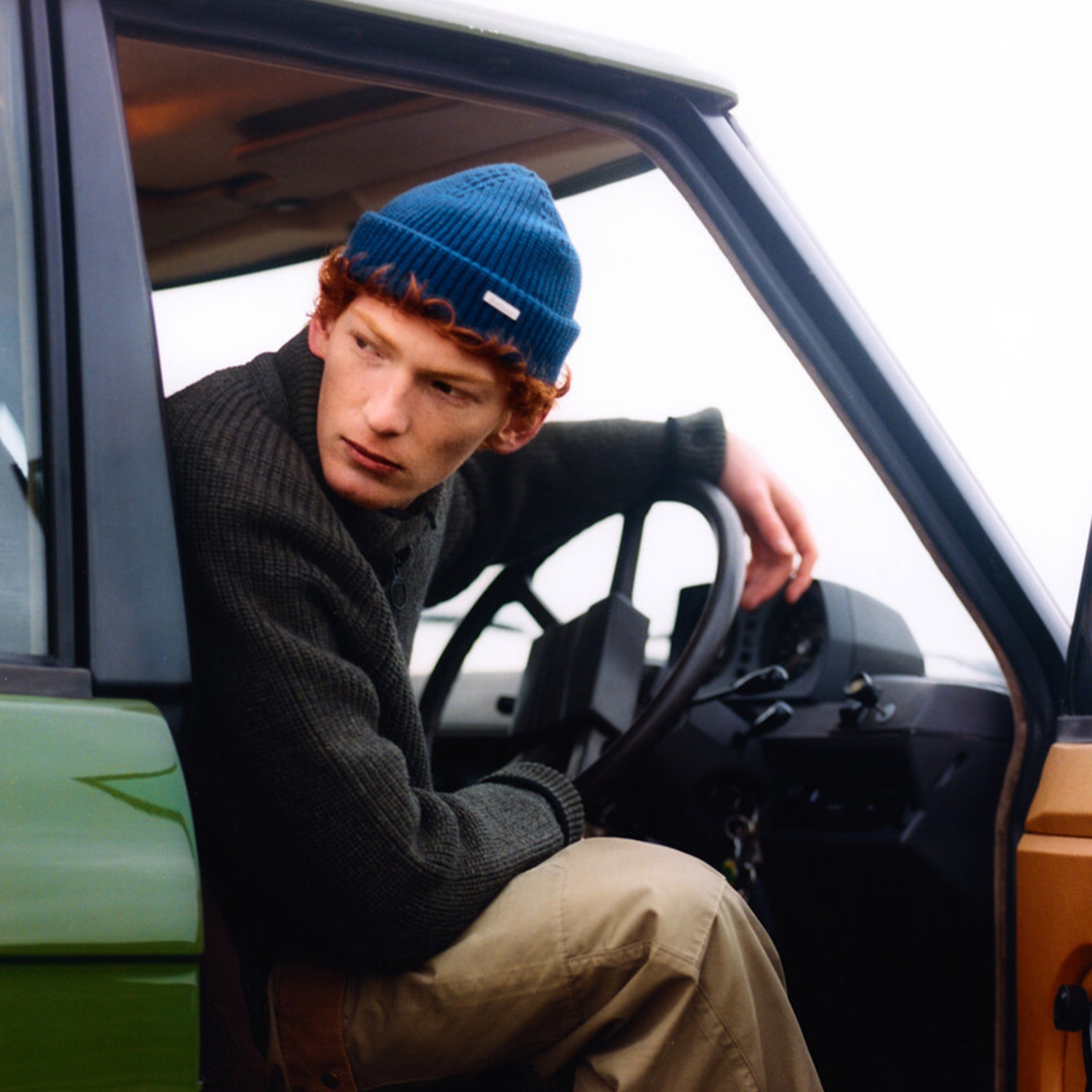 Barbour MOSELY Mens Beanie Inky Blue, detail view of man driving a vehicle, wearing blue beanie and sweater.