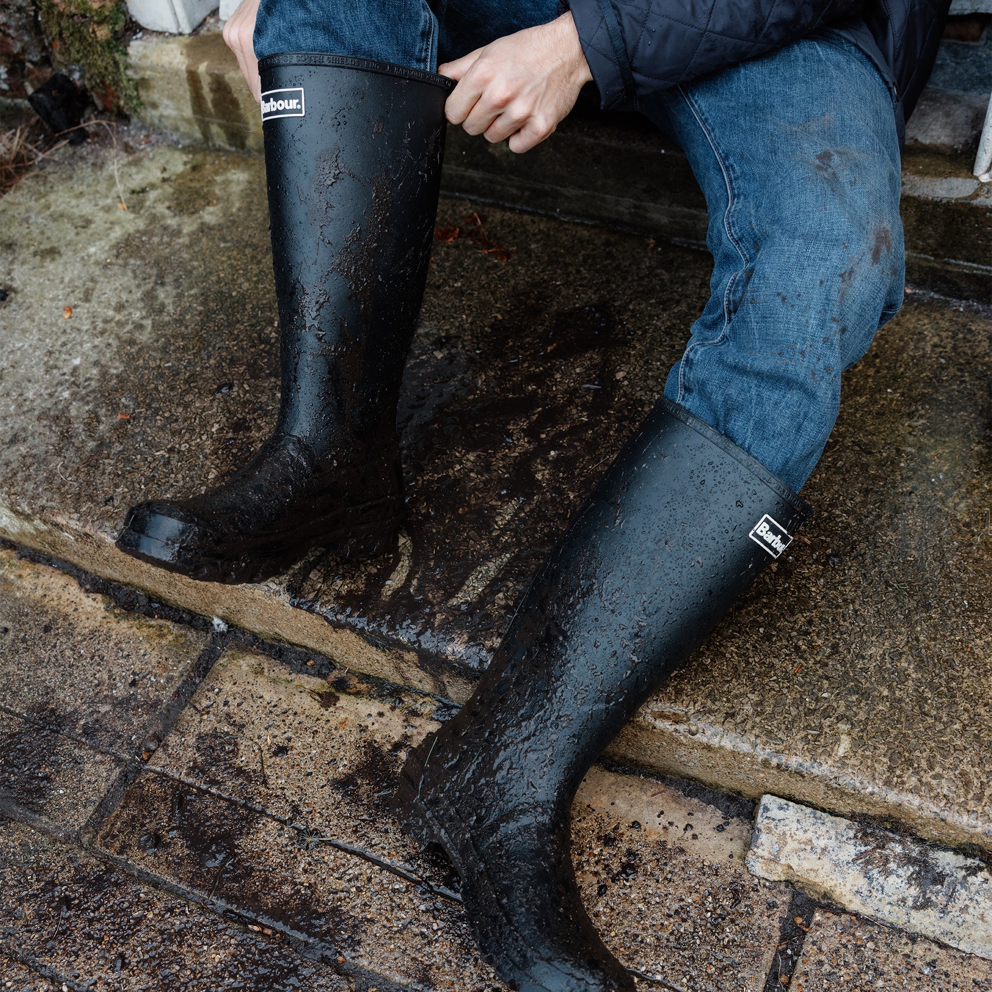 Barbour BEDE Mens Tall Wellington Boots Black side view worn outdoors, showcasing waterproof design and knee-high shaft.