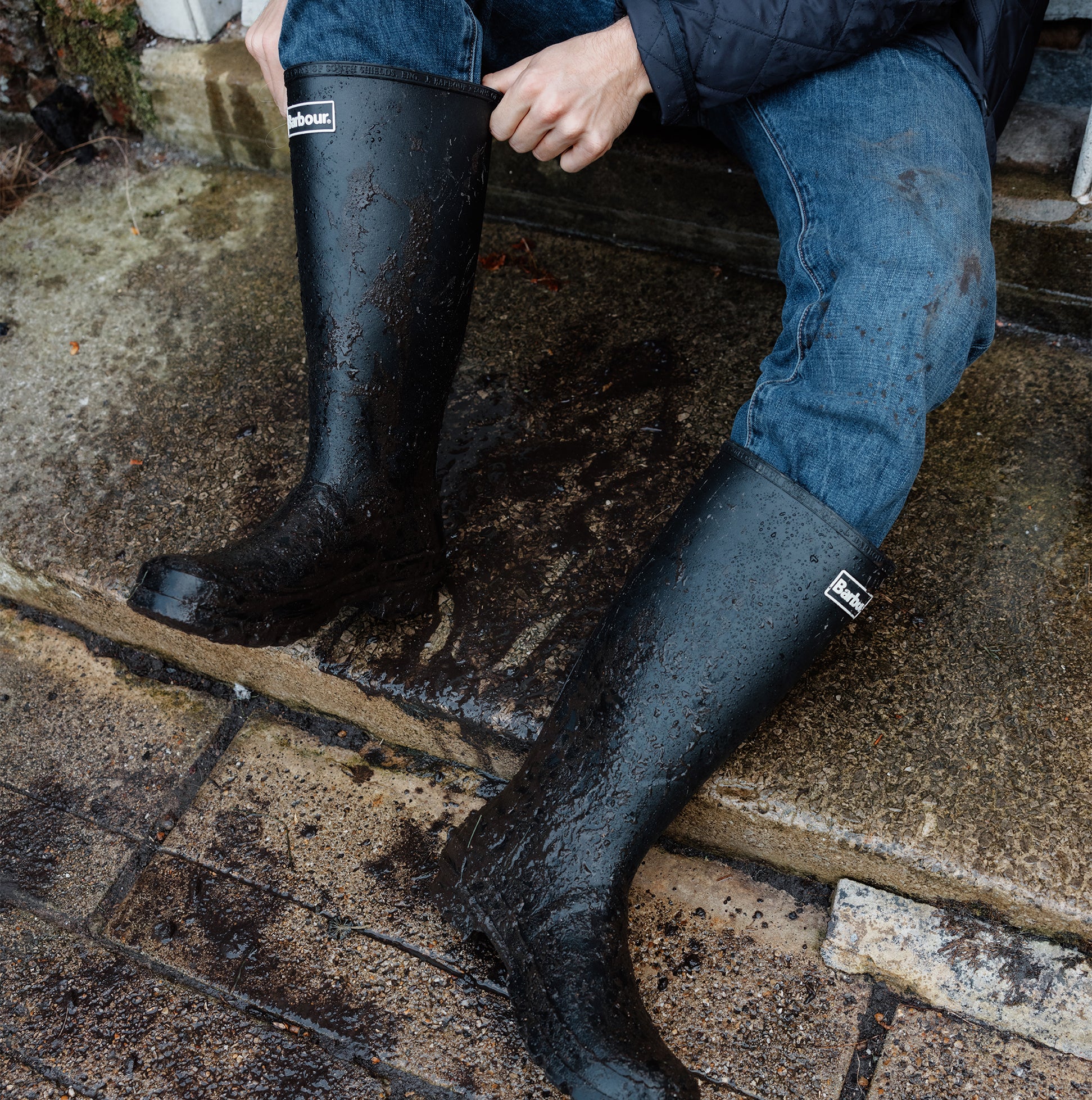 Barbour BEDE Mens Tall Wellington Boots Black side view worn outdoors, showcasing waterproof design and knee-high shaft.