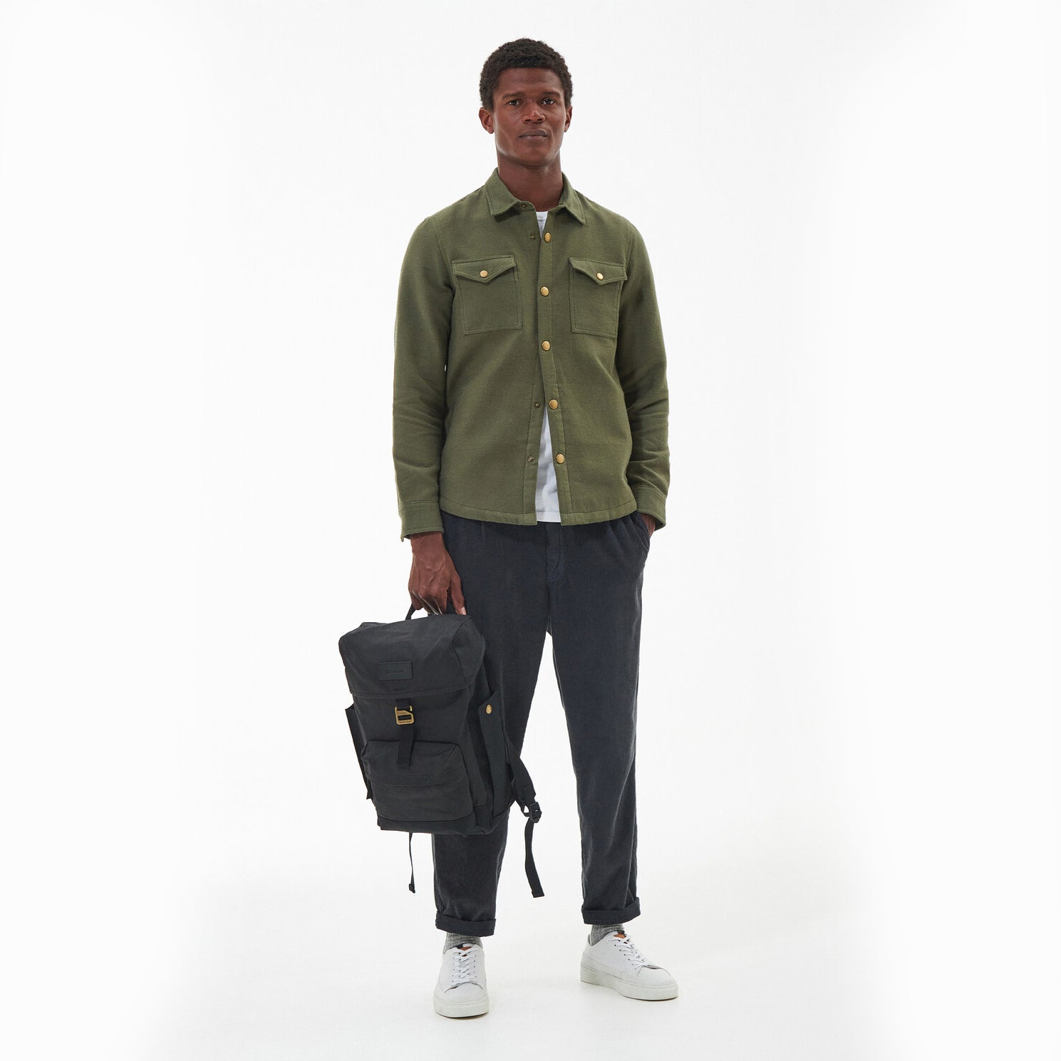 Barbour ESSENTIAL WAX BACKPACK Unisex Adults Backpack Black front view held by a model dressed in casual attire.