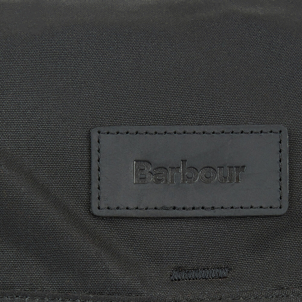 Barbour ESSENTIAL WAX BACKPACK Unisex Adults Backpack Black detail view of embossed Barbour badge on fabric.