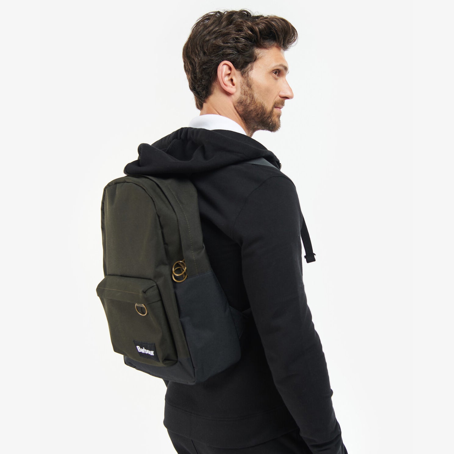 Barbour HIGHFIELD CANVAS BACKPACK Unisex Adults Canvas Backpack Navy/Olive side view on model wearing black hoodie.