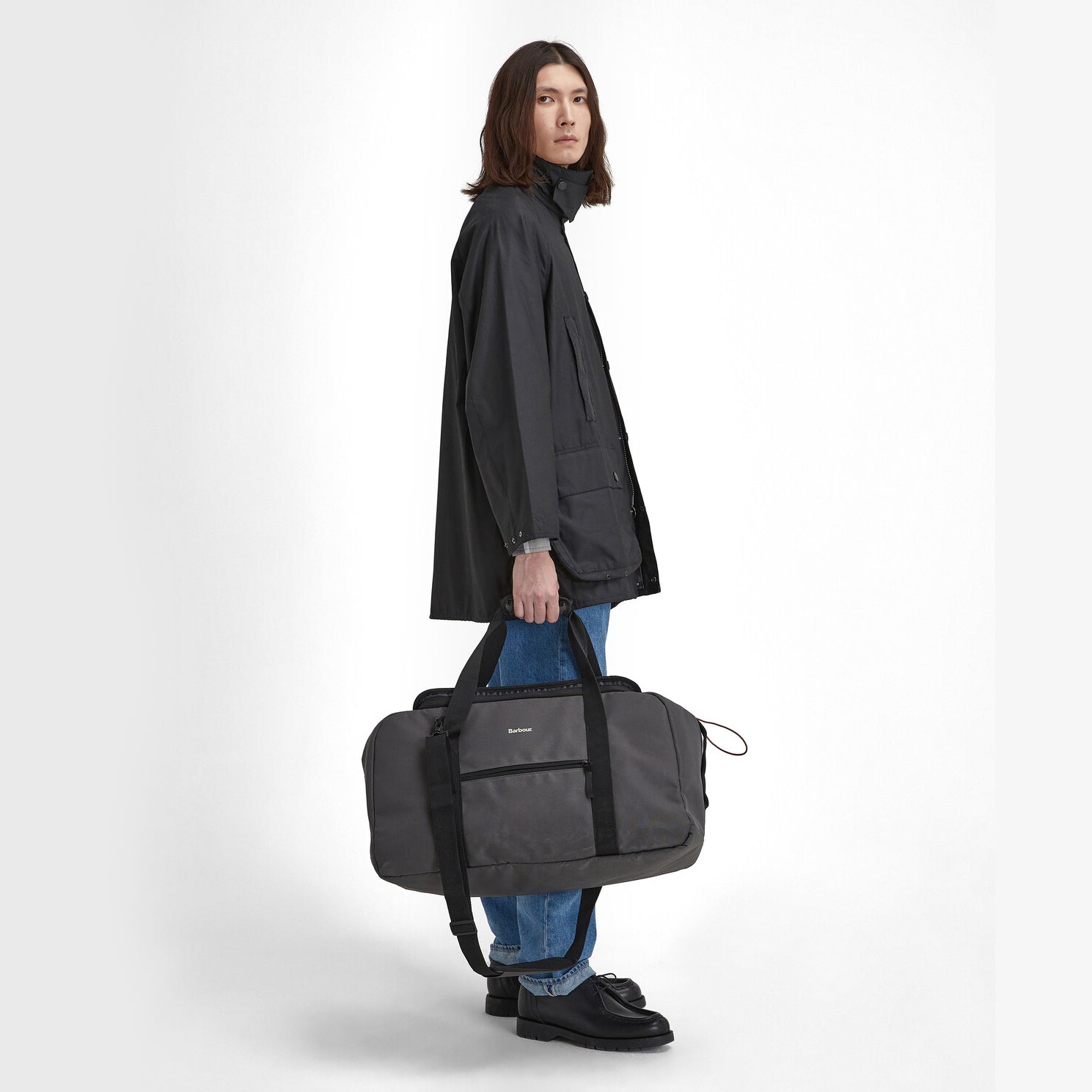 Barbour ARWIN CANVAS Unisex Adults Duffle Bag Charcoal/Ginger side view with model holding the bag.