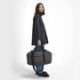 Barbour ARWIN CANVAS Unisex Adults Duffle Bag Charcoal/Ginger side view with model holding the bag.