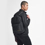 Barbour KNOCKHILL ESSENTIAL BACKPACK Unisex Adults Backpack Black side view on model wearing black jacket.