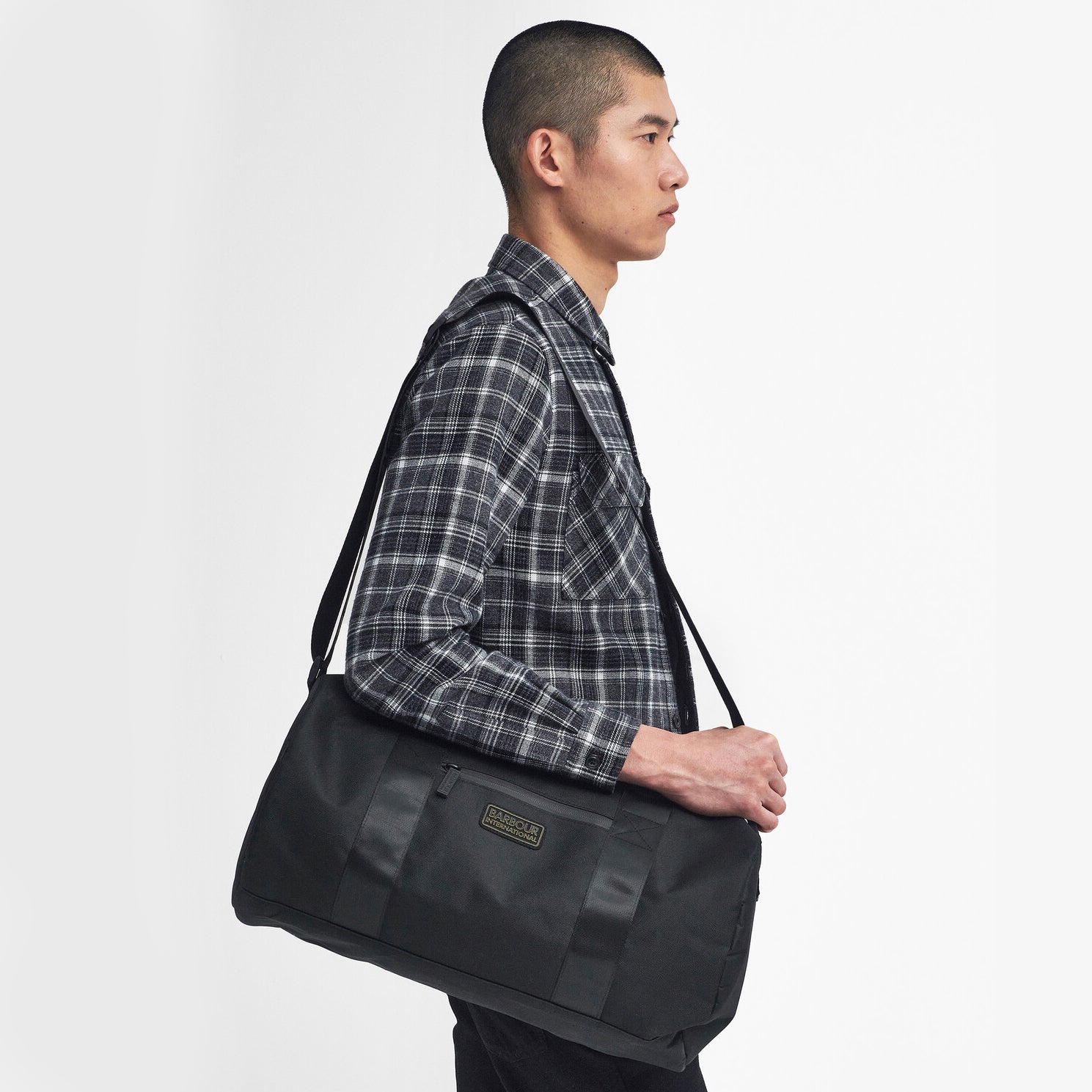 Barbour KNOCKHILL ESSENTIAL HOLDALL Unisex Adults Holdall Black side view held by a man, showcasing its spacious design.