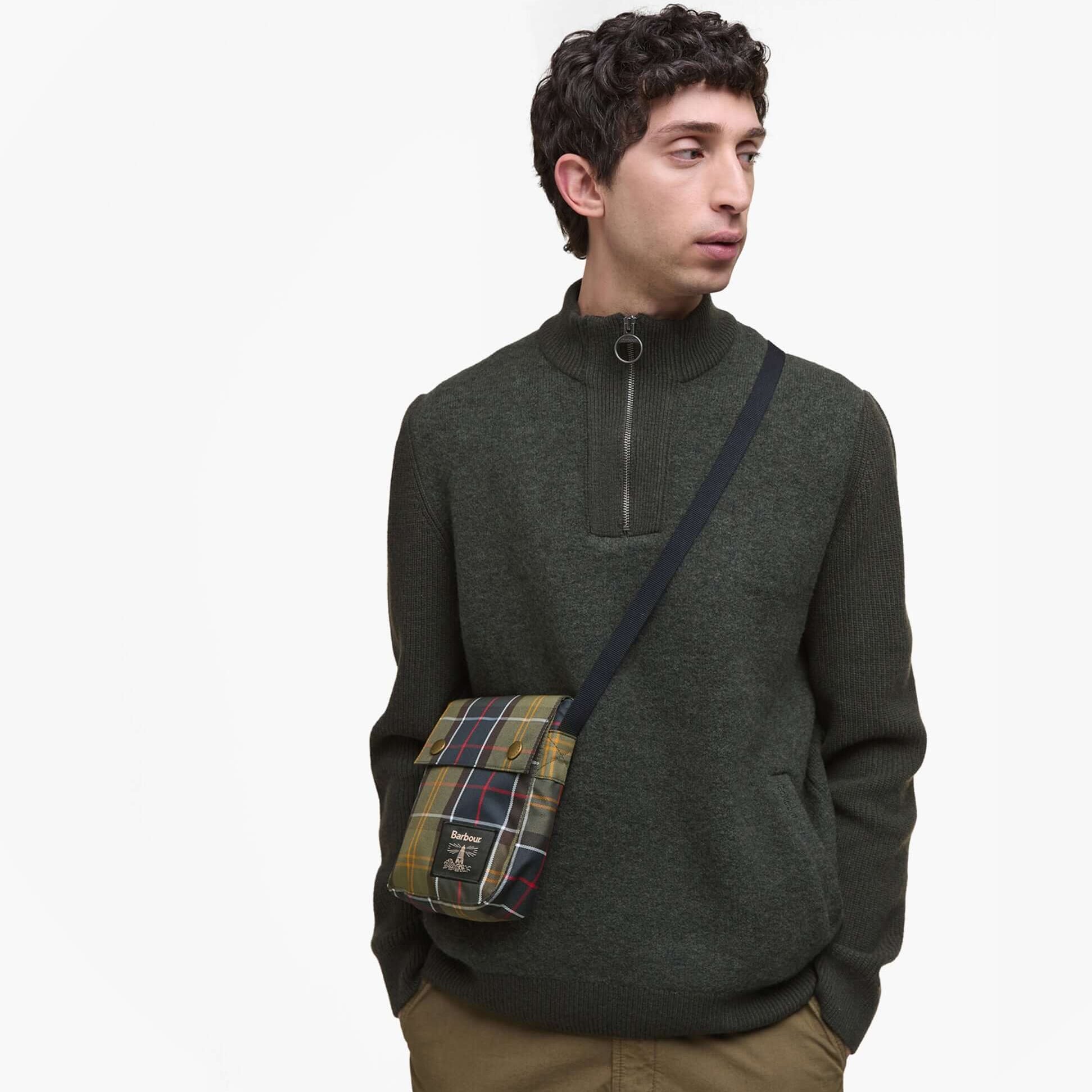 Barbour TORRIDON TARTAN Mens Flight Bag Classic Tartan worn crossbody, featuring classic tartan design, model in sweater.