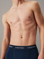Calvin Klein COTTON STRETCH Mens 3 Pack Trunks Multicoloured side view of model wearing navy trunks with Calvin Klein waistband.