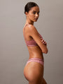 Calvin Klein TONAL LOGO COTTON Womens Thong Red Grape W/ Apple Butter Logo side view on model showcasing fit and design.
