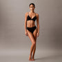 Calvin Klein CK ESTABLISHED Womens Thong Black side view model wearing thong and matching top against gray background.
