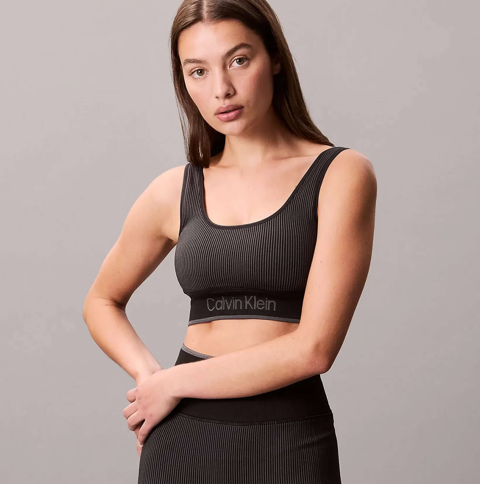 Calvin Klein Medium Impact Womens Sports Bra Black front view with model wearing it, showing ribbed texture and brand logo.