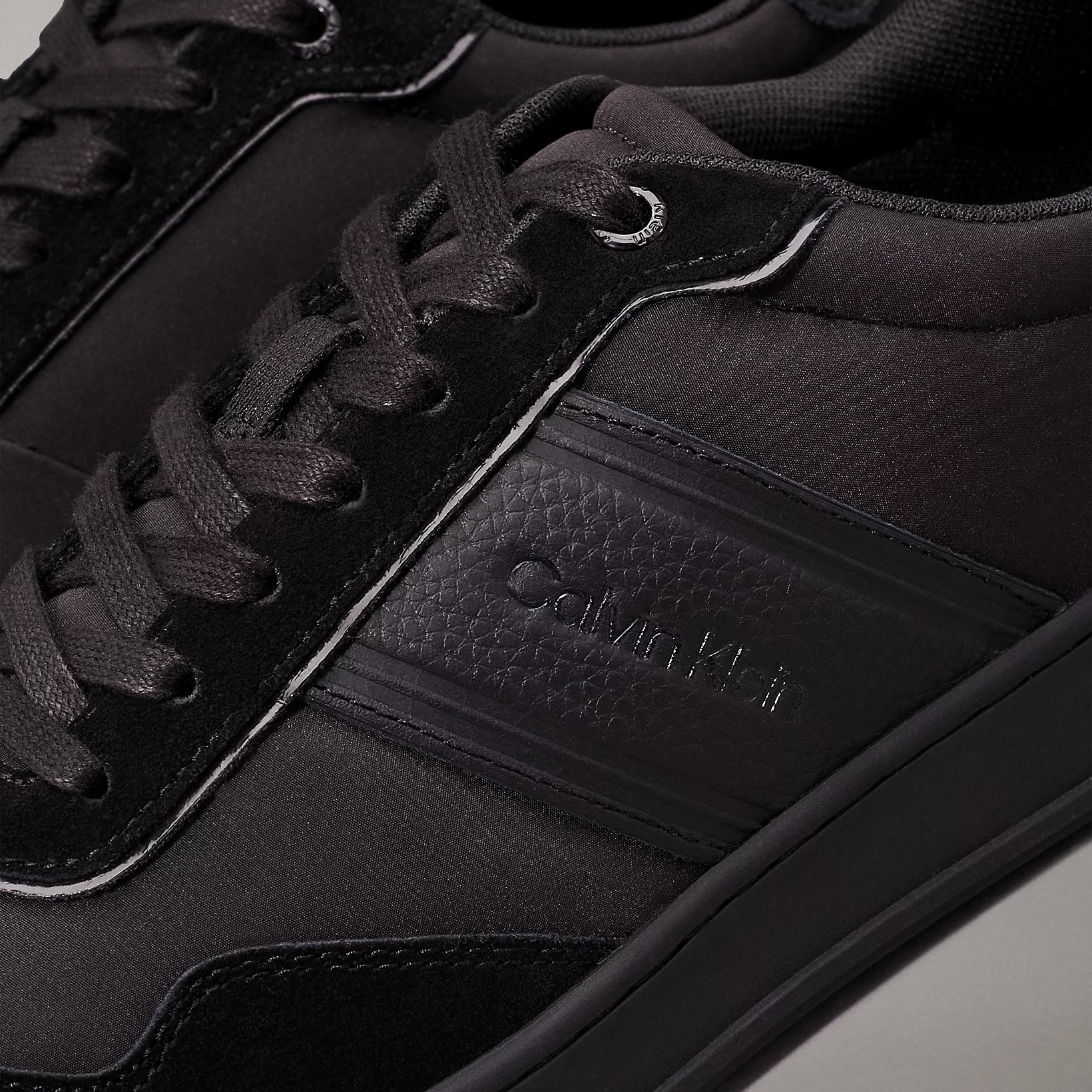 Calvin Klein LOW TOP LACE UP MIX Mens Trainers Triple Black close-up detail view showcasing black laces and material.