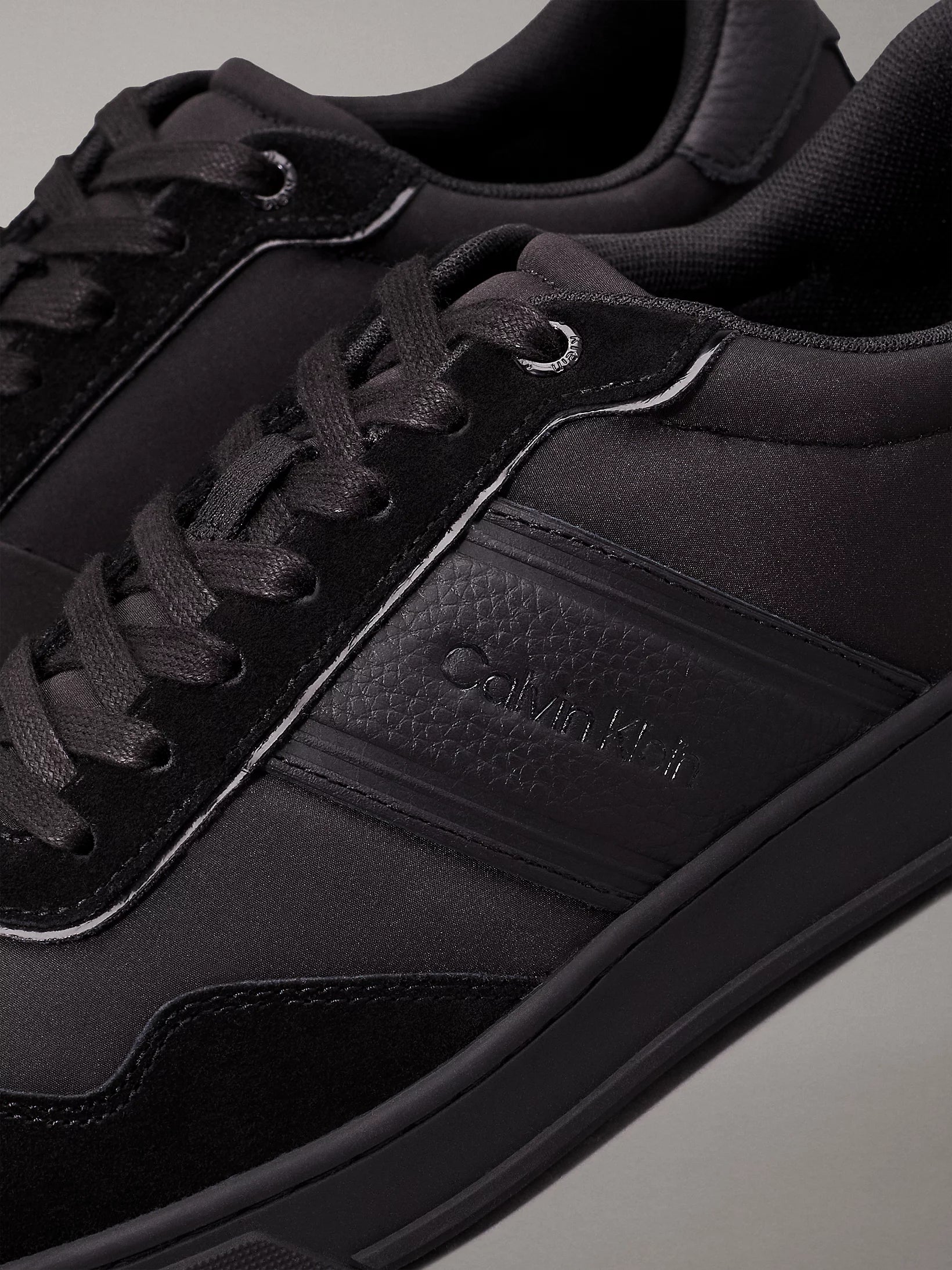 Calvin Klein LOW TOP LACE UP MIX Mens Trainers Triple Black close-up detail view showcasing black laces and material.