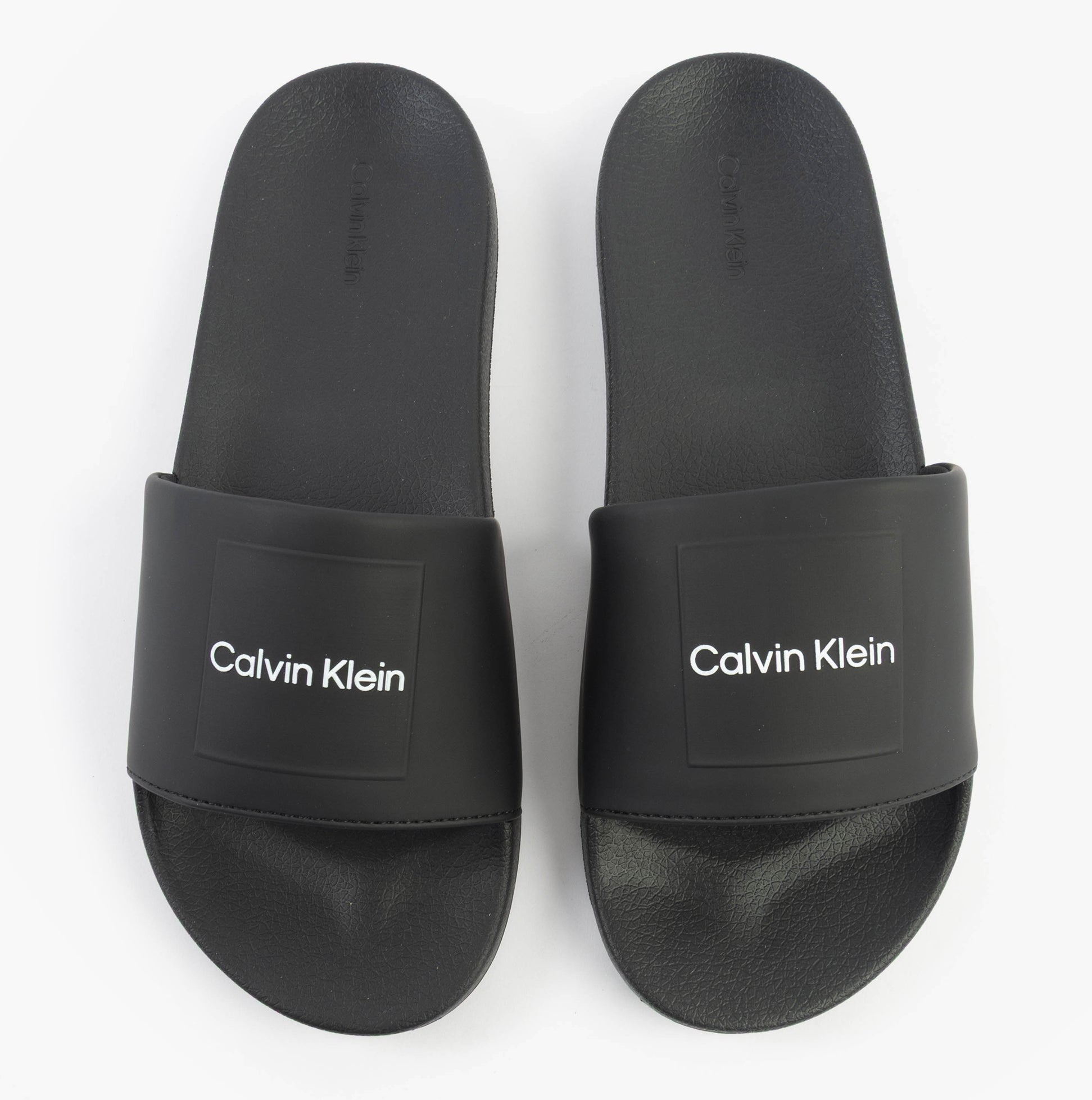 Calvin Klein POOL SLIDE W/ CK SQU Mens Sliders Black top view showing synthetic upper and flat rubber sole.