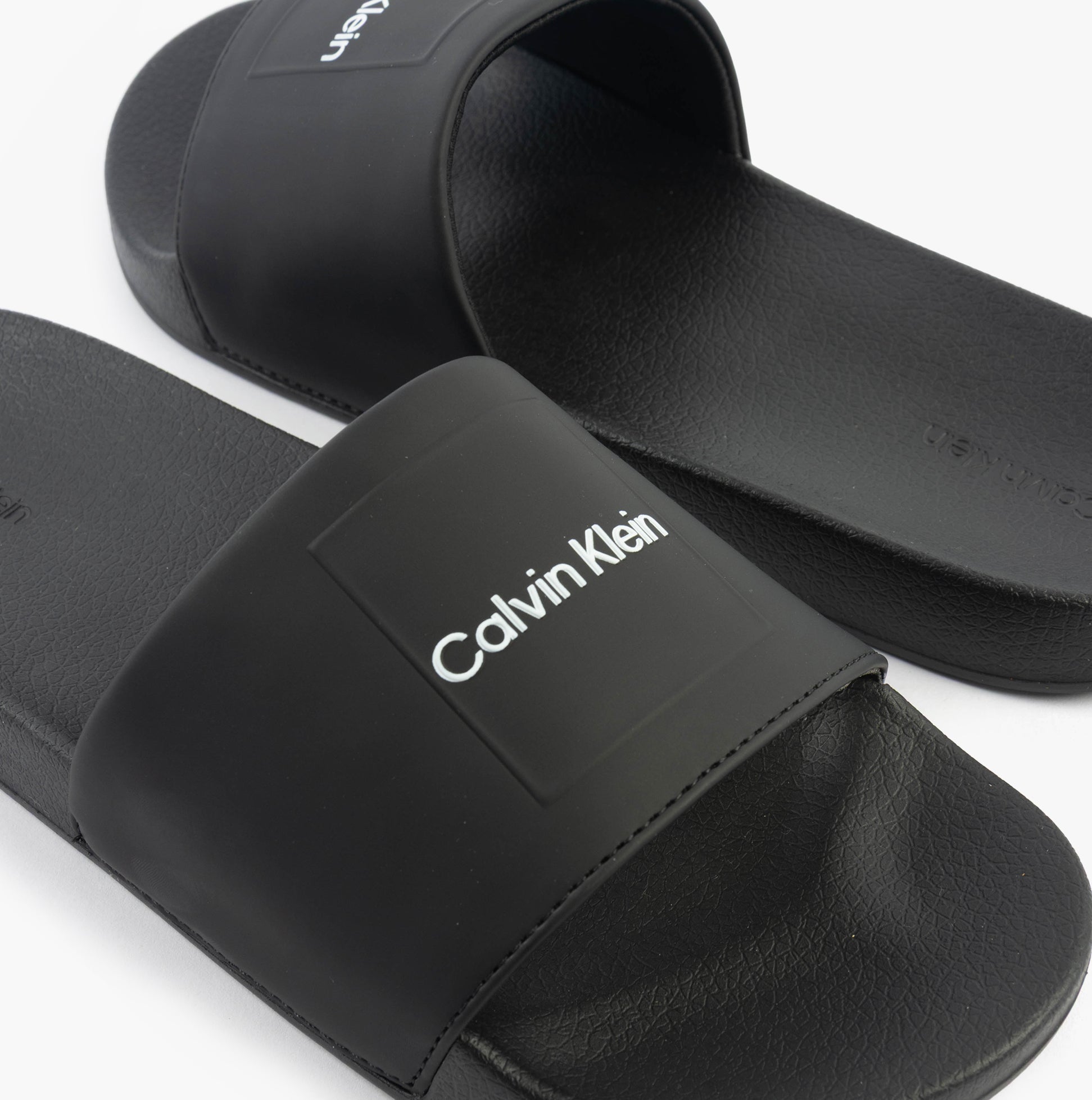 Calvin Klein POOL SLIDE W/ CK SQU Mens Sliders Black side view showing synthetic upper and slip-on design.