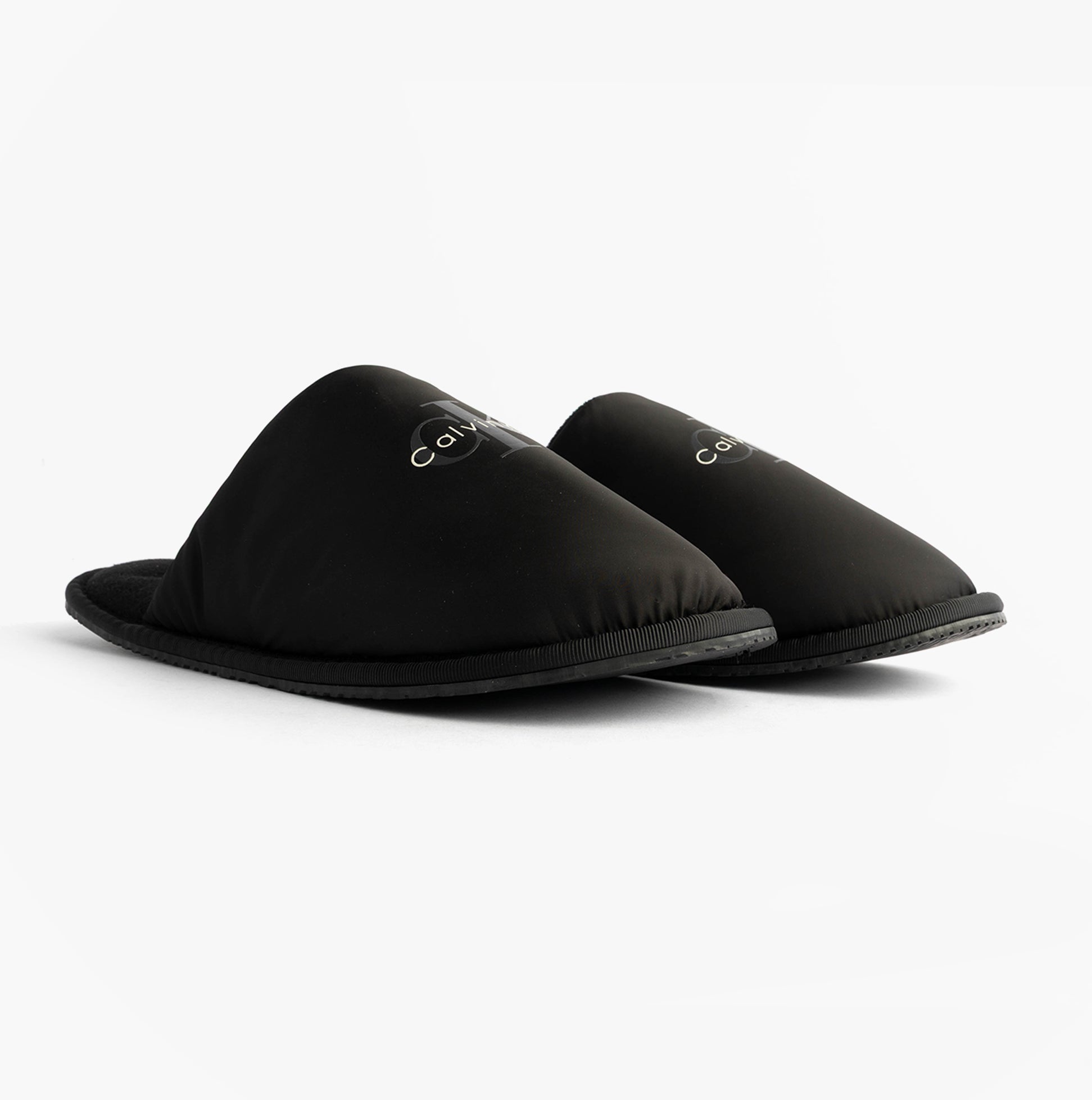 Calvin Klein HOTEL SLIPPER MONOLOGUE Mens Slippers Triple Black side view showing lightweight mules with slip-on design.