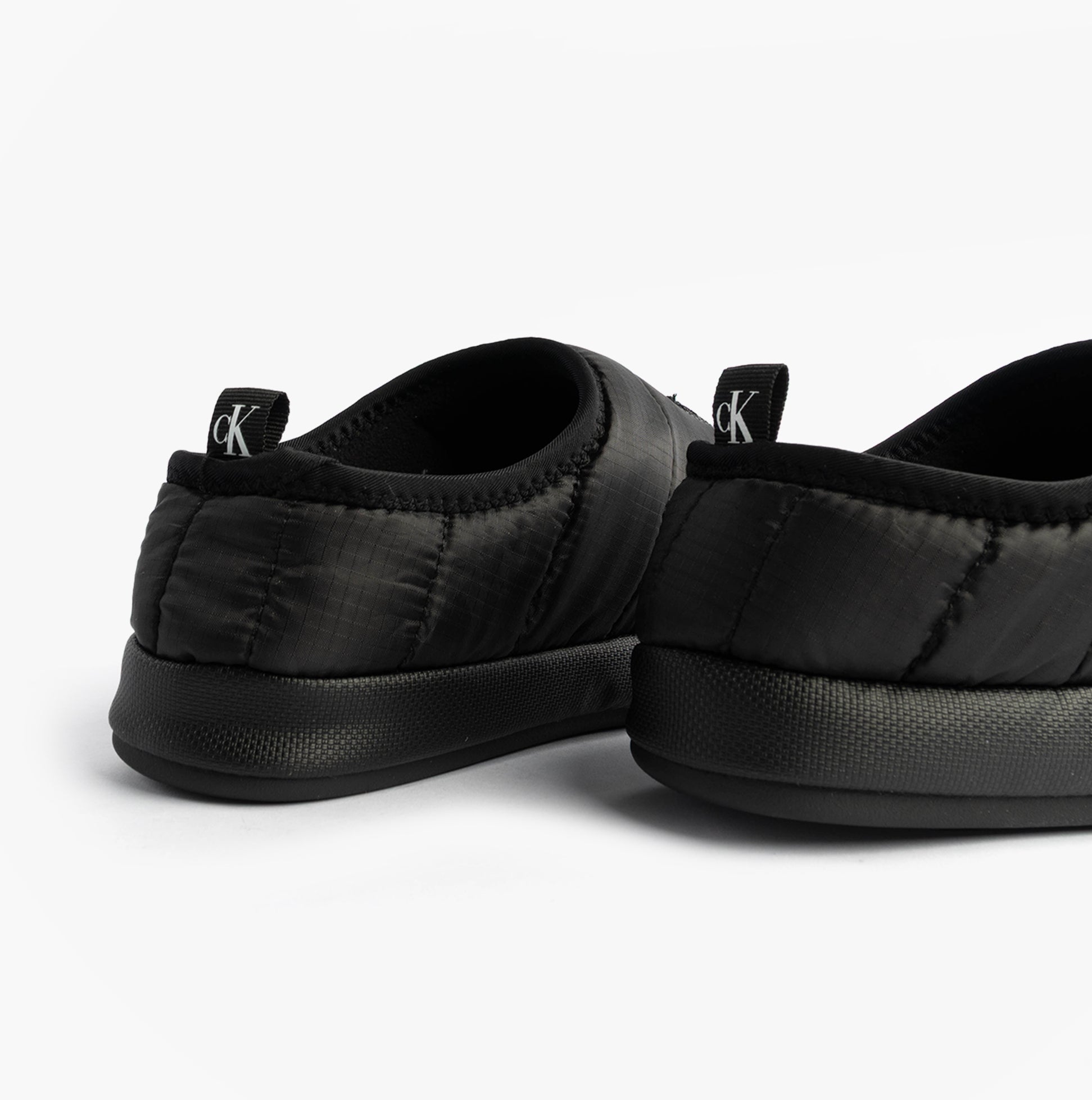 Calvin Klein HOME SLIPPER NYL PAT Womens Slippers Black rear view showing soft polyester upper and flat sole.