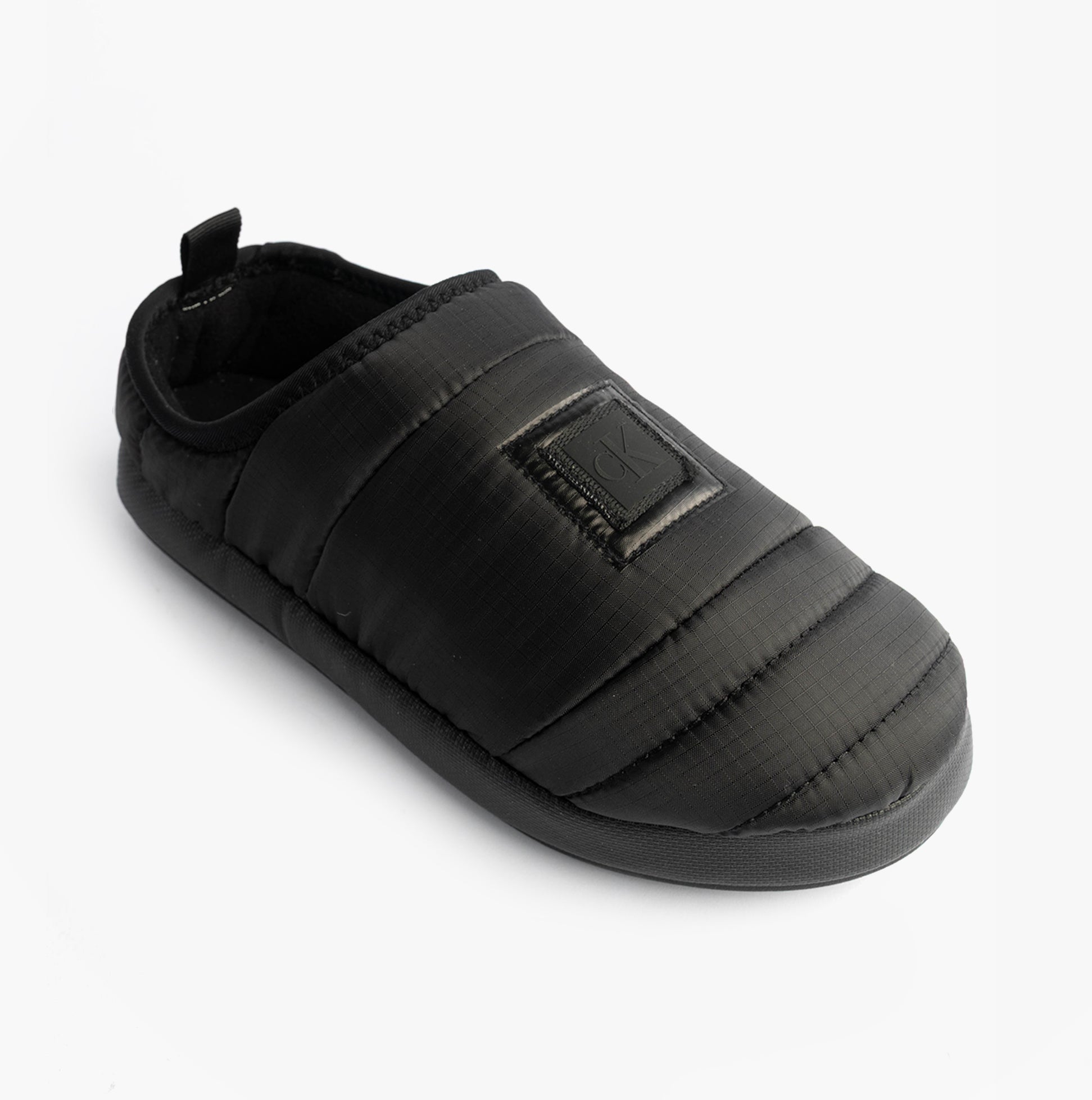 Calvin Klein HOME SLIPPER NYL PAT Womens Slippers Black side view showcasing soft polyester upper and slip-on design.