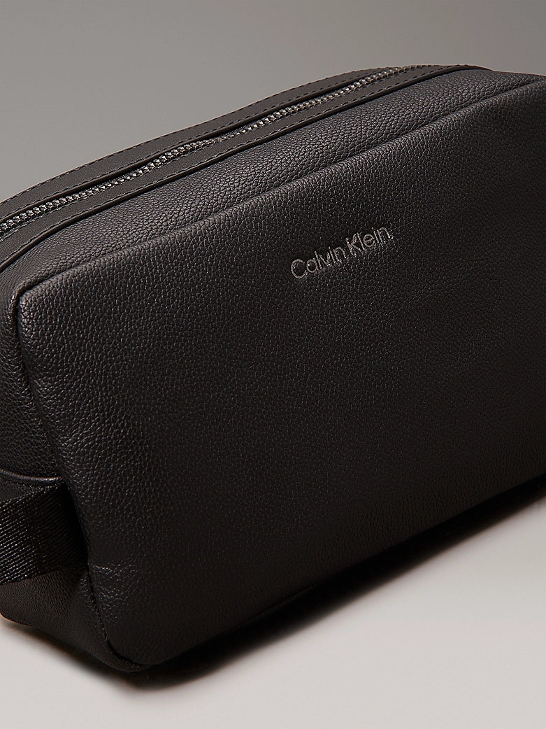Calvin Klein WARMTH WASHBAG Mens Black front view with zip closure and CK logo on faux leather exterior.