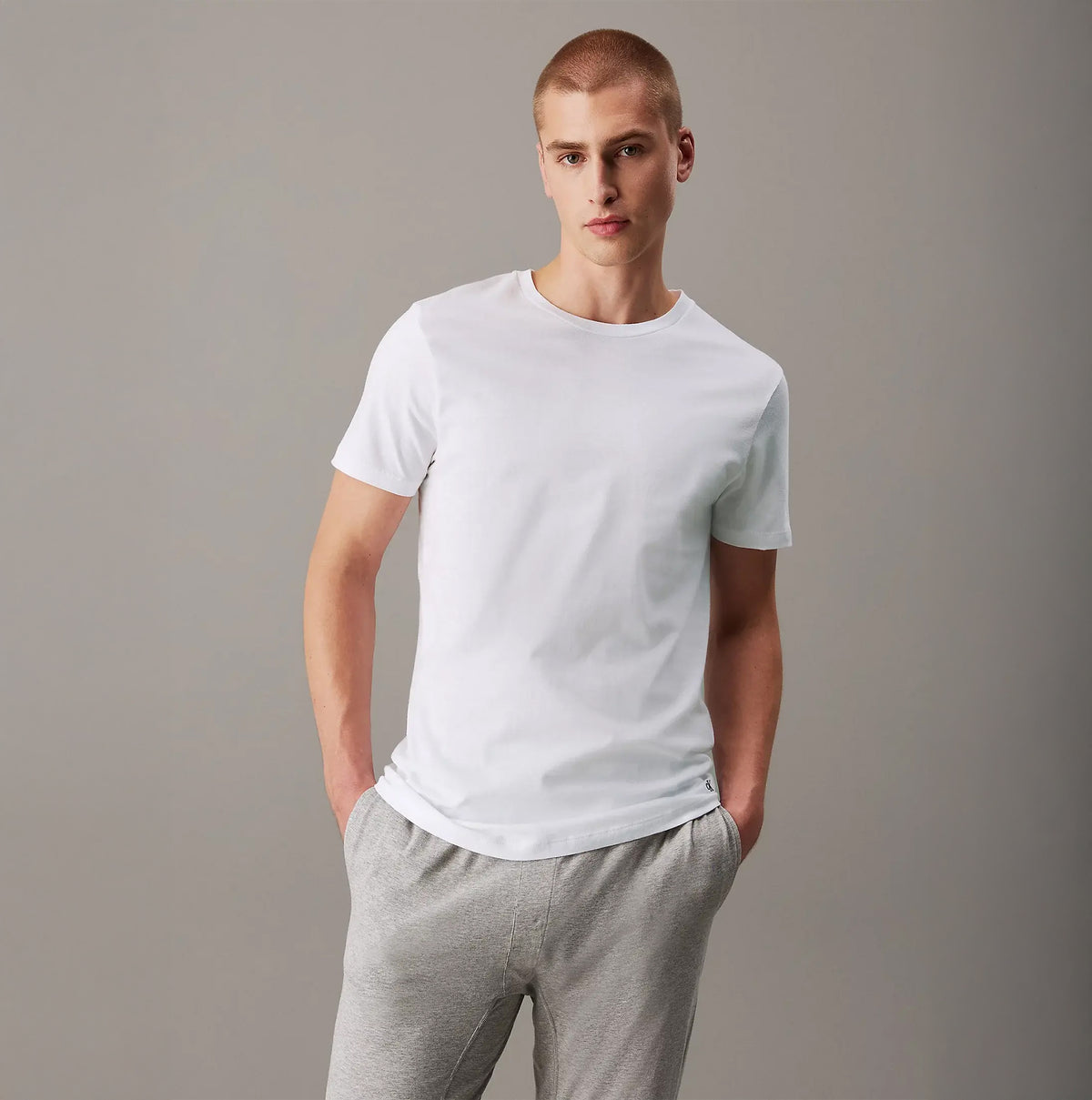 Calvin Klein 100% COTTON 3 Pack Mens T-Shirts White front view on male model wearing casual gray pants.