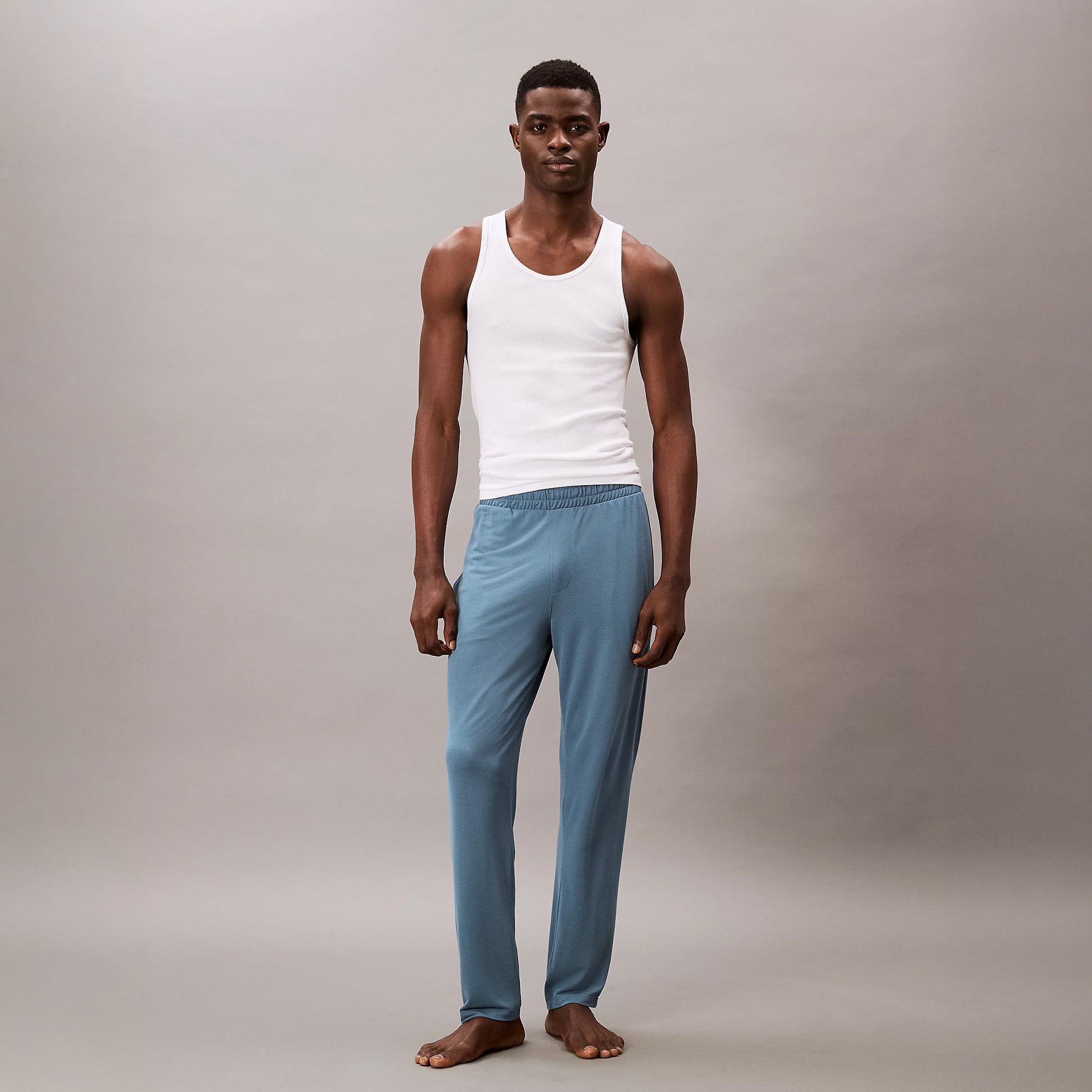 Calvin Klein SLEEP PANT Mens Deck Gray front view on model wearing a white tank top and demonstrating comfortable jogger style.