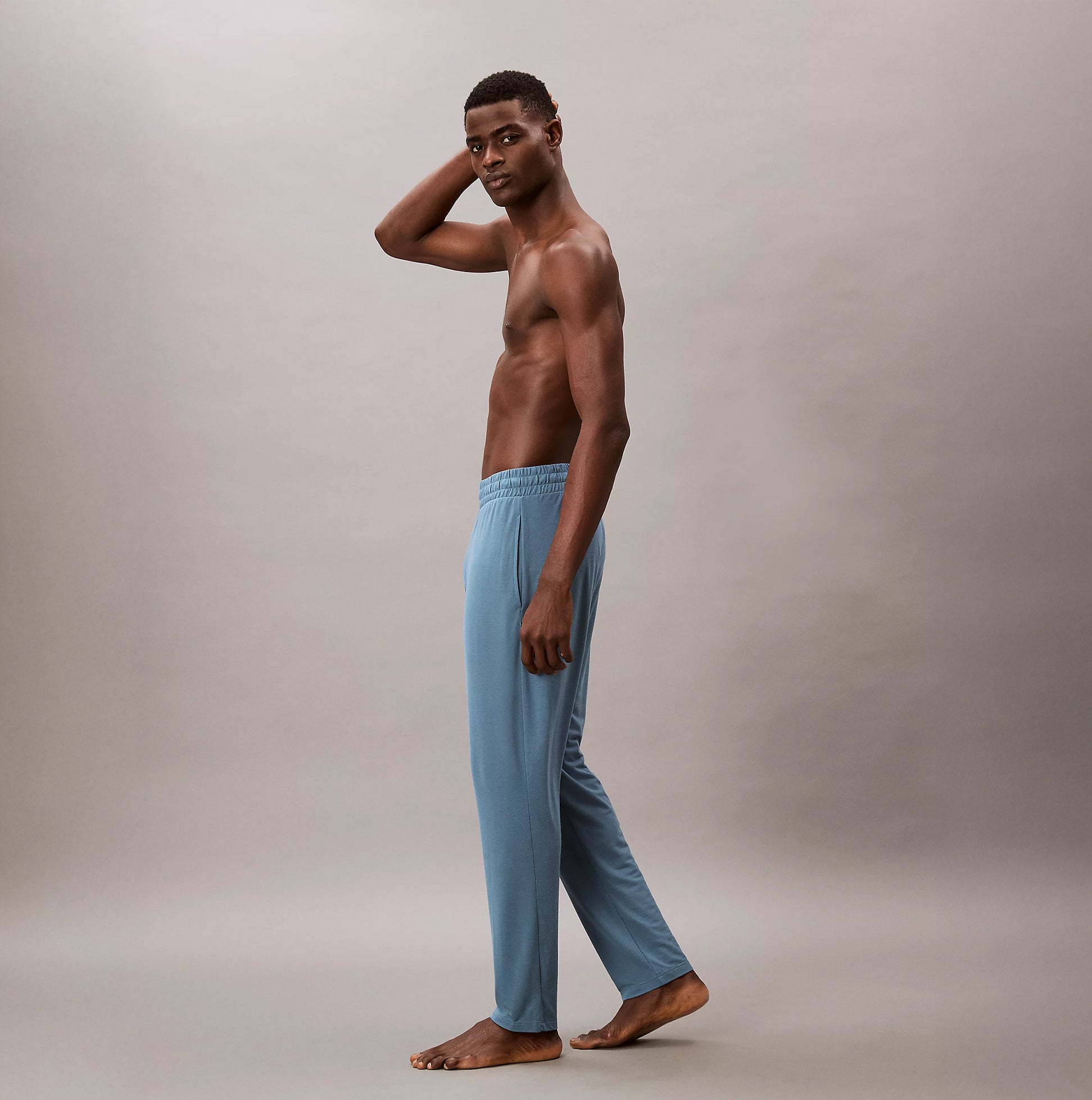 Calvin Klein SLEEP PANT Mens Deck Gray side view, fitted elastic waist joggers in light gray, model standing barefoot.