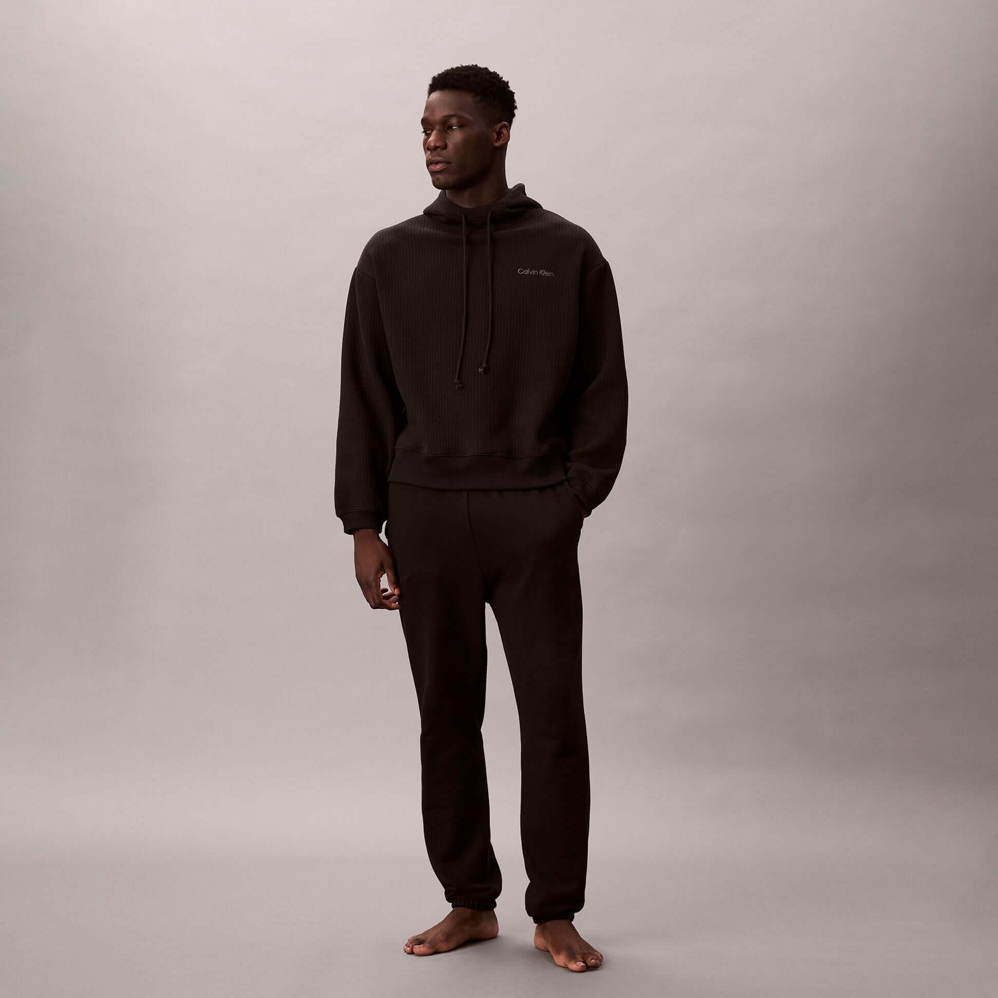 Calvin Klein QUILTED HOODIE Mens Hoodies Black on model, side view, showcasing long sleeves and relaxed fit.