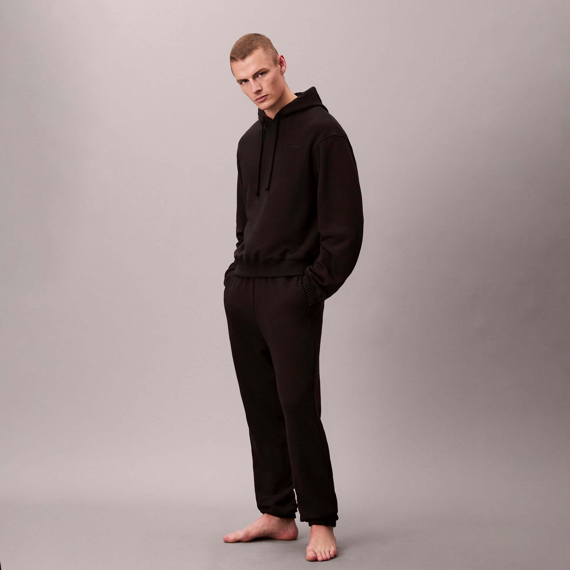 Calvin Klein L/S HOODIE Mens Hoodie Black front view, model wearing relaxed fit black hoodie and matching pants.