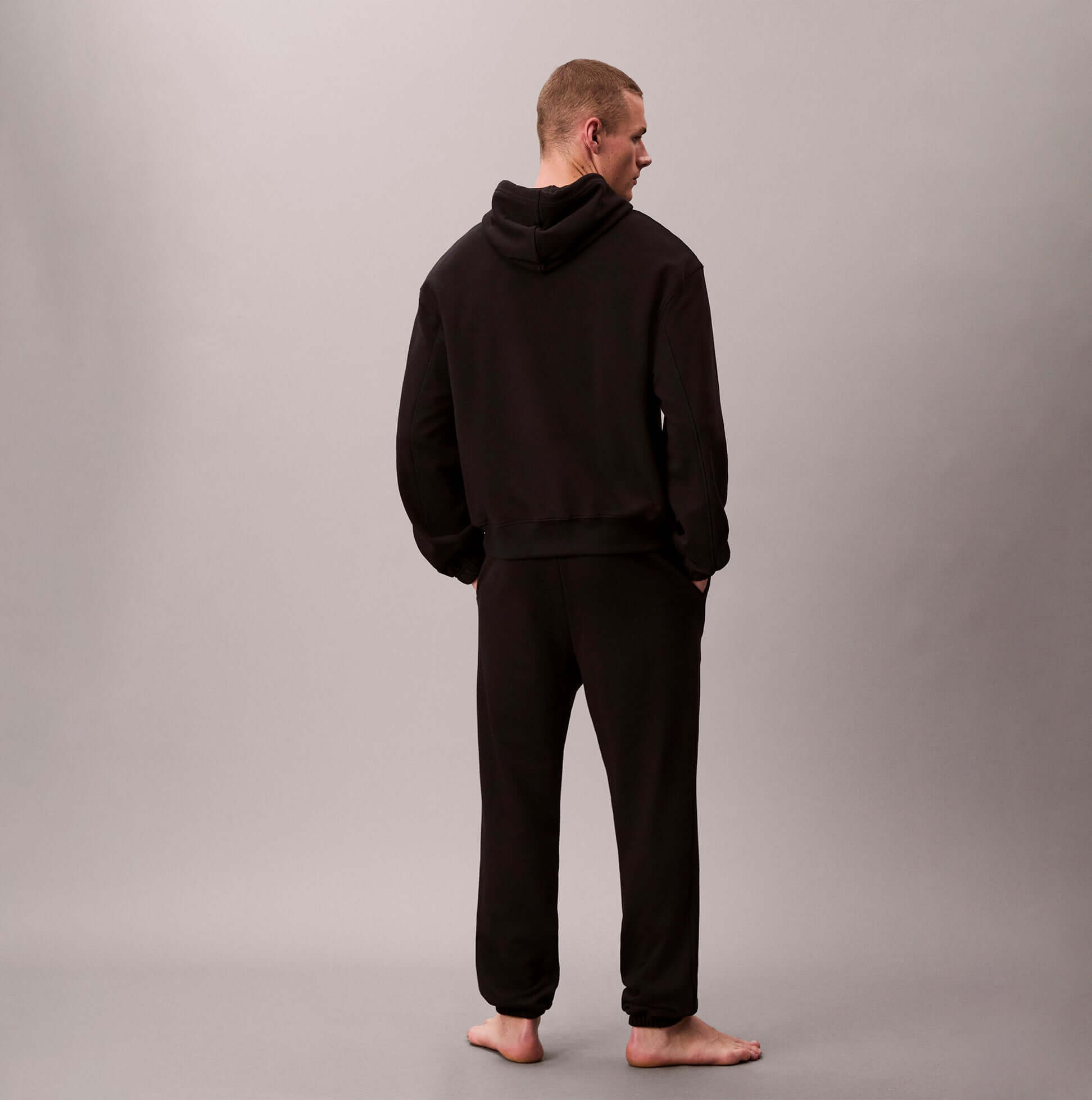 Calvin Klein L/S HOODIE Mens Hoodie Black back view on a model wearing black sweatpants.