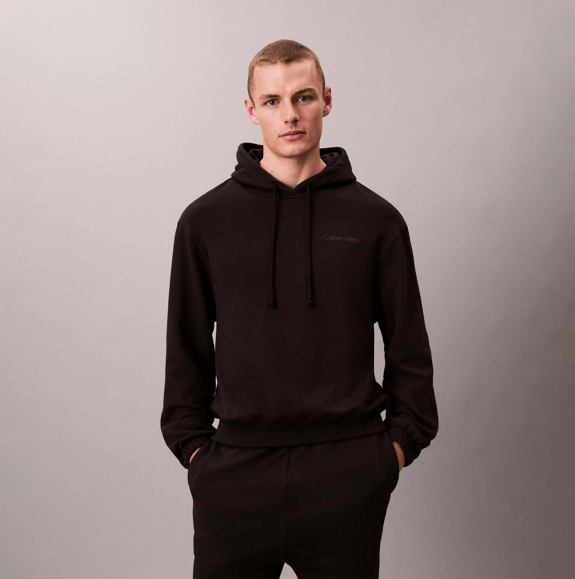 Calvin Klein L/S HOODIE Mens Hoodie Black front view with model wearing the hoodie, featuring relaxed fit and drawstring.