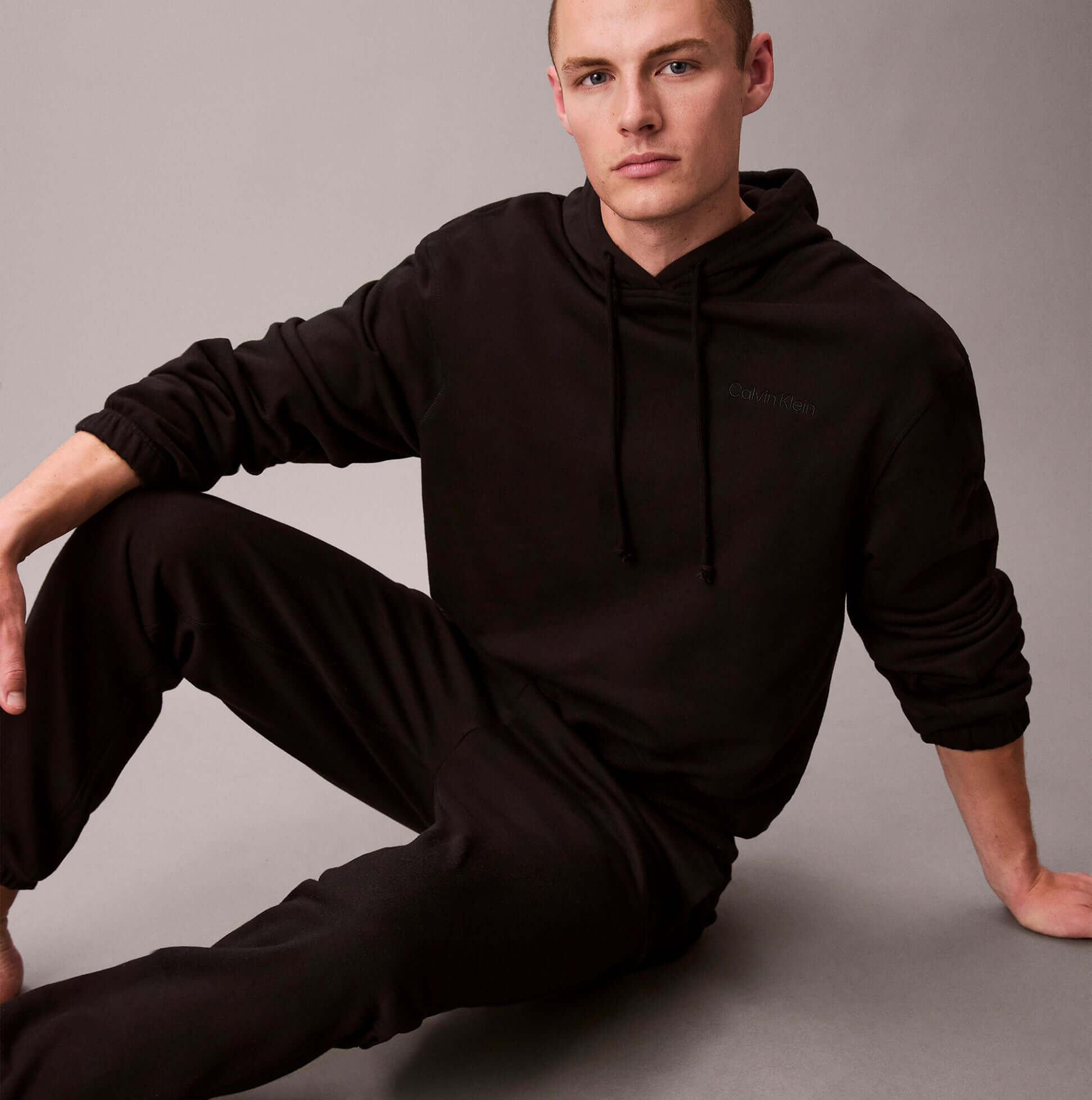 Calvin Klein JOGGER Mens Black front view, stylish black jogger outfit worn by a model sitting, comfortable casual wear.