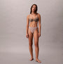 Calvin Klein Bonded Flex Seamless 3 Pack Thong Multi styled on model in front view, showcasing thong and bra in natural colors.