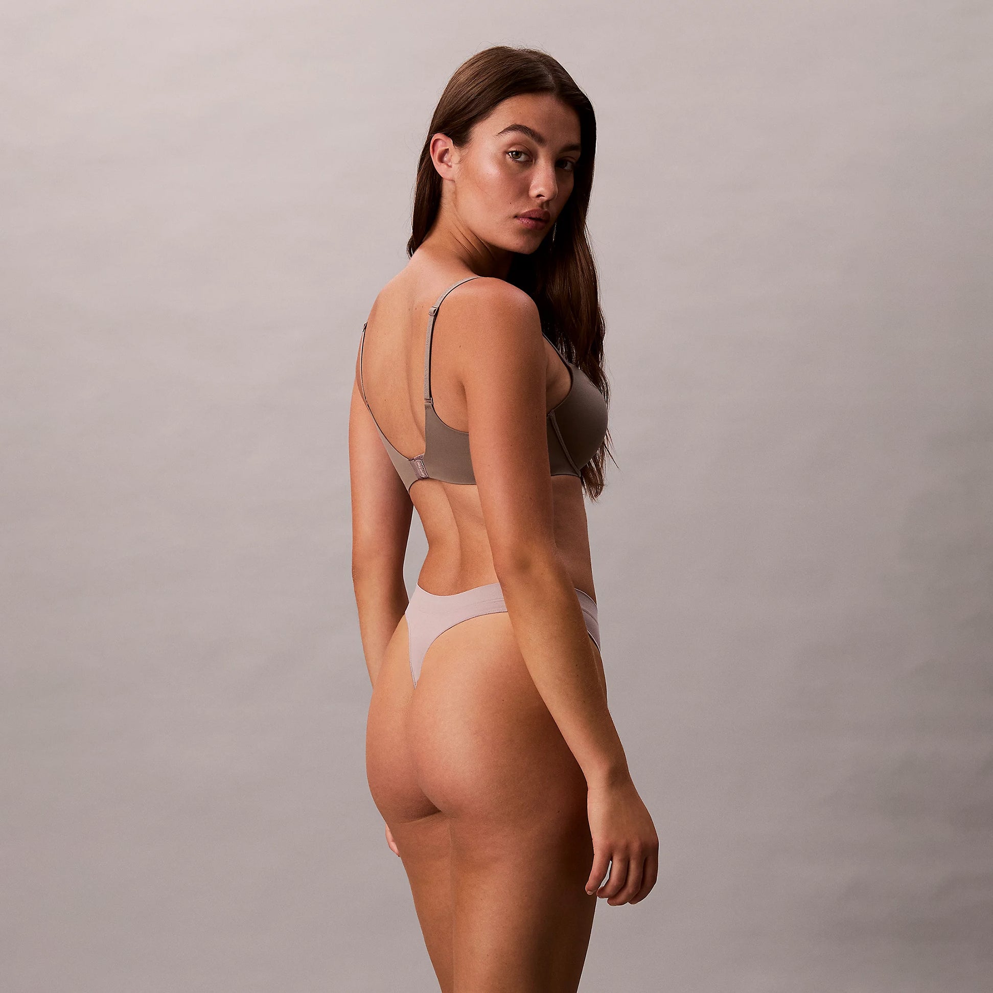 Calvin Klein Bonded Flex Seamless 3 Pack Thong Multi side view of model wearing thong with smooth fabric details.