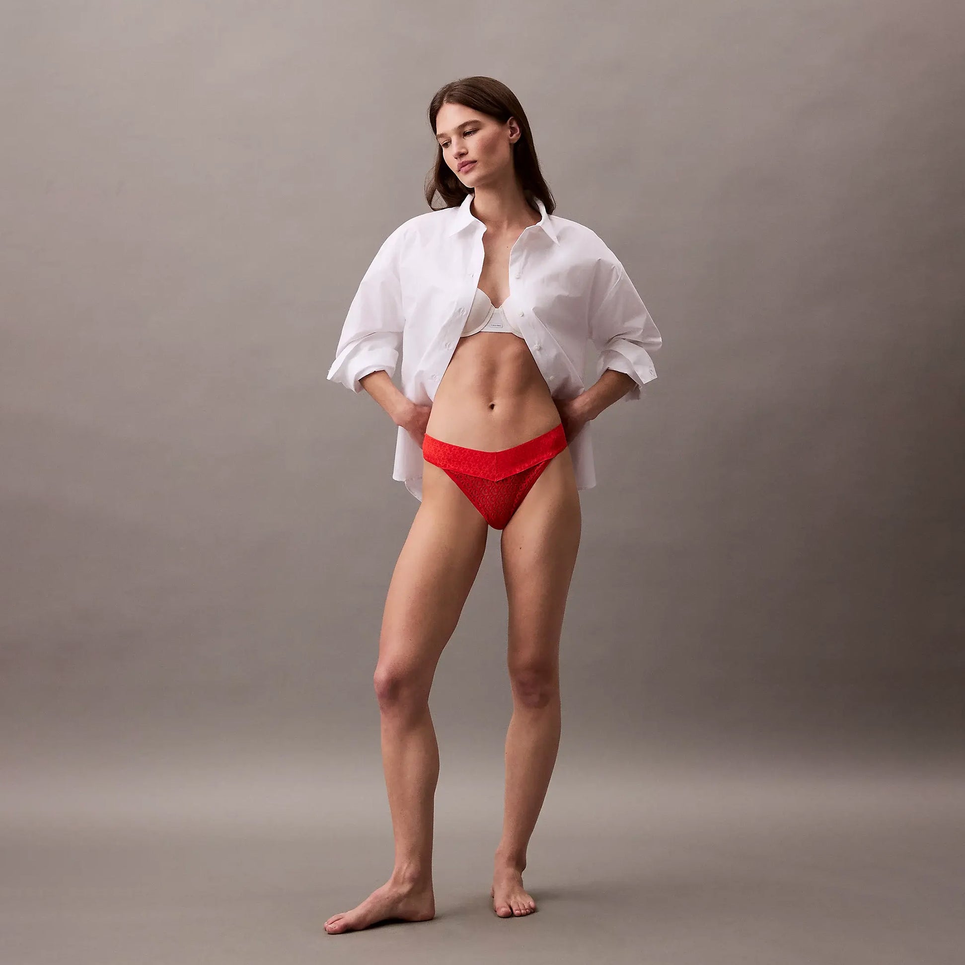 Calvin Klein THONG Womens Icon Logo Lace Molten Red side view model wearing a white shirt and red lace thong.